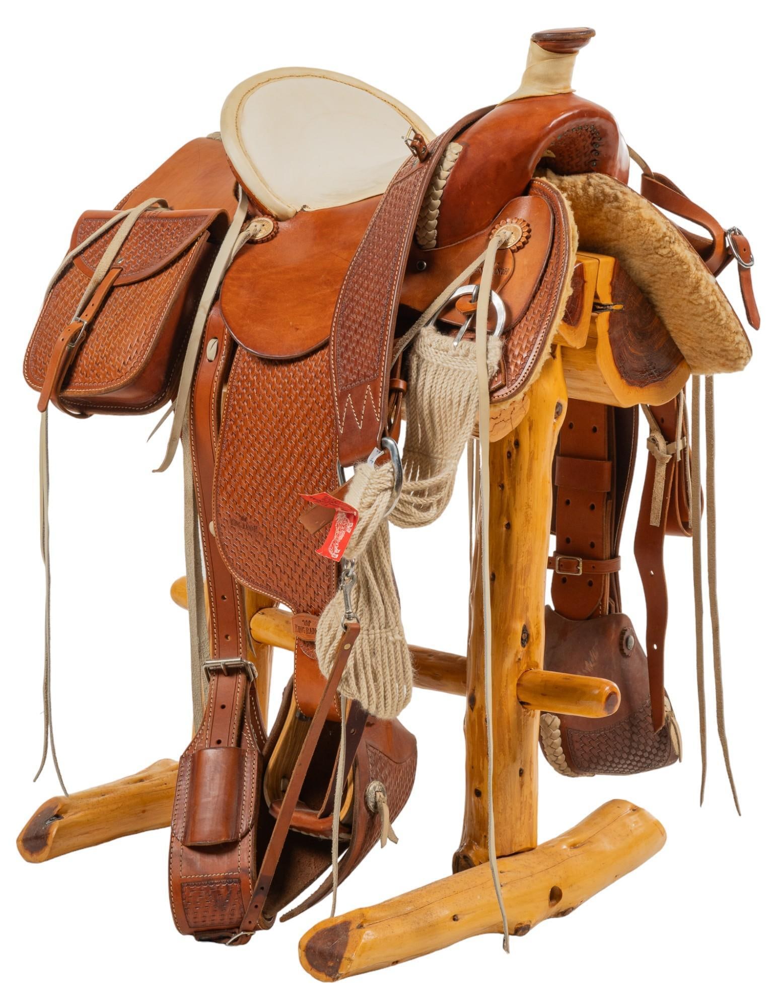 King Ranch Saddle and Stand: King Ranch saddle and stand, saddle with matching breast collar, hooded leather stirrups, mohair cinch, set of saddle bags, all pieces monogrammed with "SH" height 39.5 in. x width 30.5 in. x 