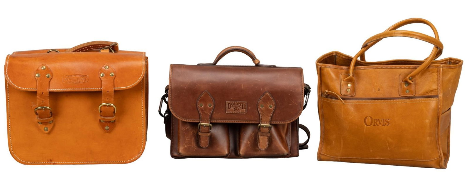 (3) Leather Travel Bags: Three leather travel bags, one is a large open top purse with two leather handles and two side pockets, embossed "LA", one is a Duluth Trading Co. briefcase with two interior and front pockets