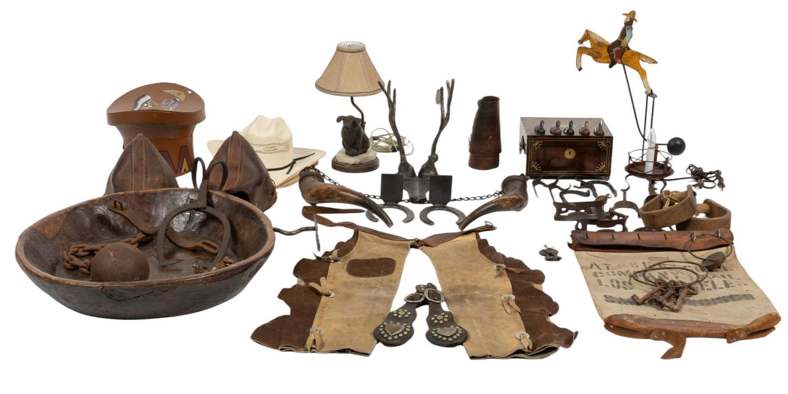 Collection of Rustic Accents: Collection of rustic accents, includes iron ball and chain, metal pig lamp, dough bowl, pairs of stirrups, two straw cowboy hats, vintage horse trinket, metal antler stand, large ice tongs, and more