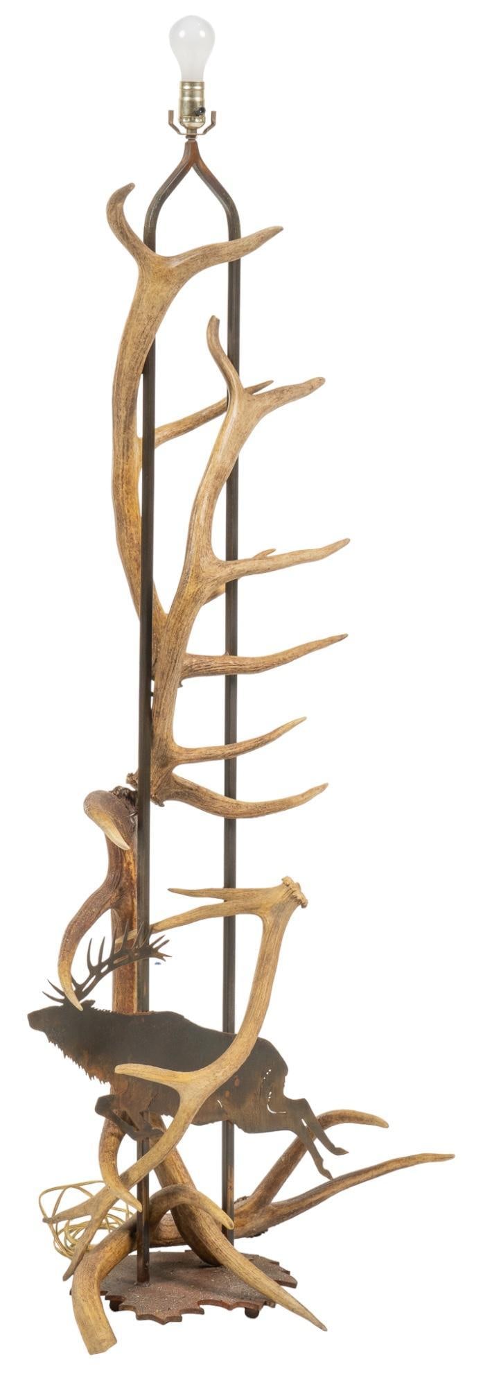 Ranch Style Floor Lamp: Ranch style floor lamp featuring elk and deer antlers, with cut metal silhouette of leaping elk, on metal base height 64.5 in. x width 28 in. x depth 18 in. Provenance: Property from the monumental li