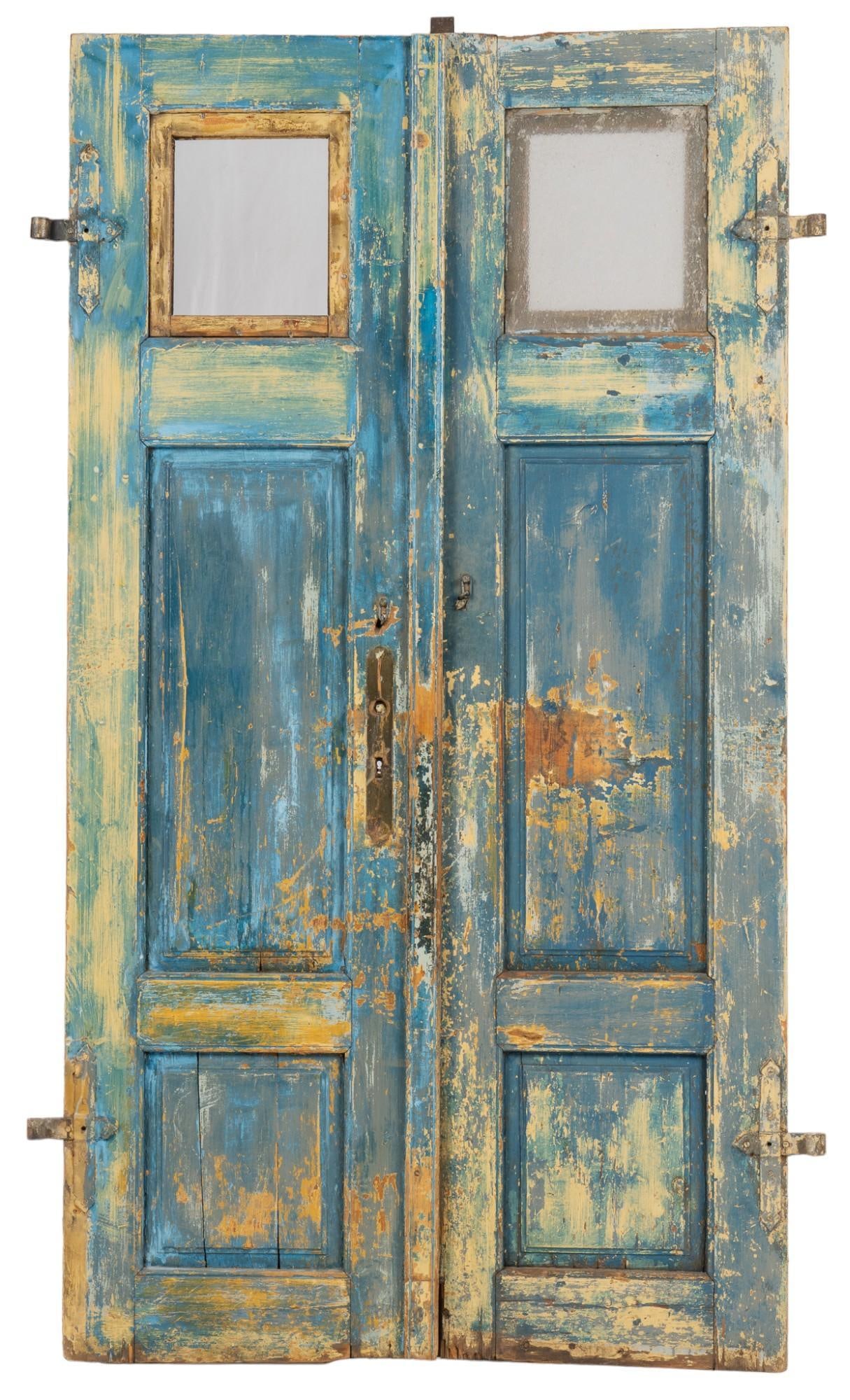 Pair of Farmhouse Doors: Pair of farmhouse doors, blue paint remnants, two square windows height 100 in. x width 58 in. x depth 6 in. Shipping available for this lot through our partner 4CL; please request a shipping quote at