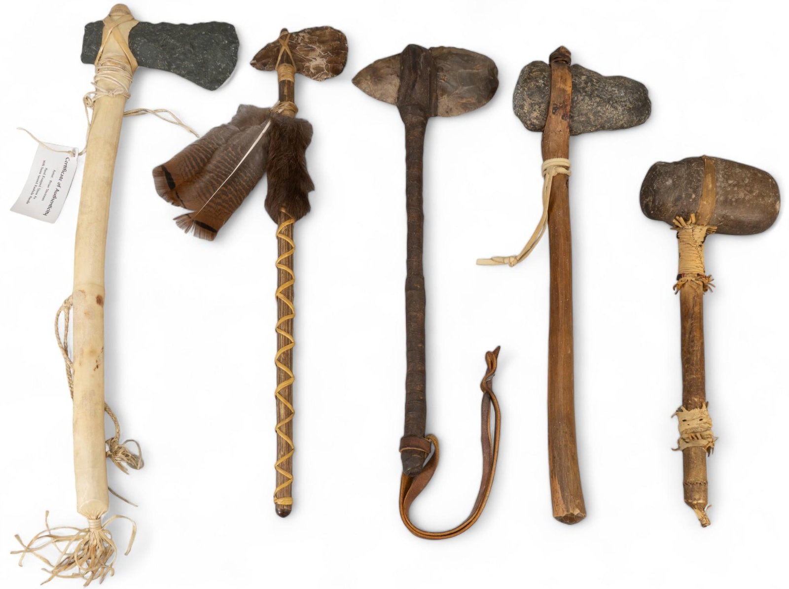Collection of (5) Flint and Stone Native American Style Axes: Collection of five flint and stone Native American style axes, includes antler and feather flint axe, buffalo jaw axe with deer leather, horn and feather stone axe, eagle motif beaded staff with feath