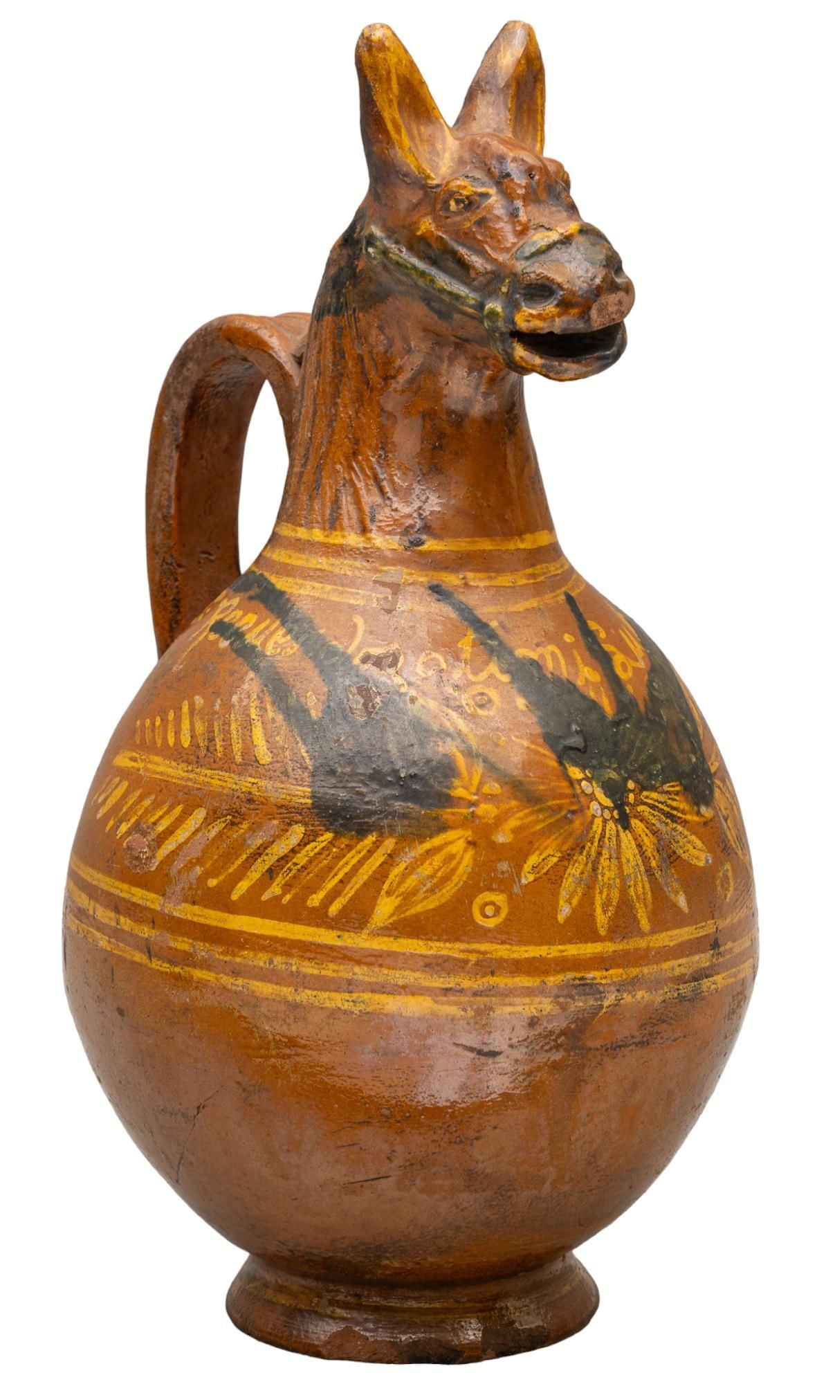 Mexican Metepec Pulque Pitcher: Metepec, pulque pitcher, painted glaze, with figural design that features donkey head motif height 14 in. x width 7 in. x depth 7 in. Shipping available for this lot through our partner 4CL; please re