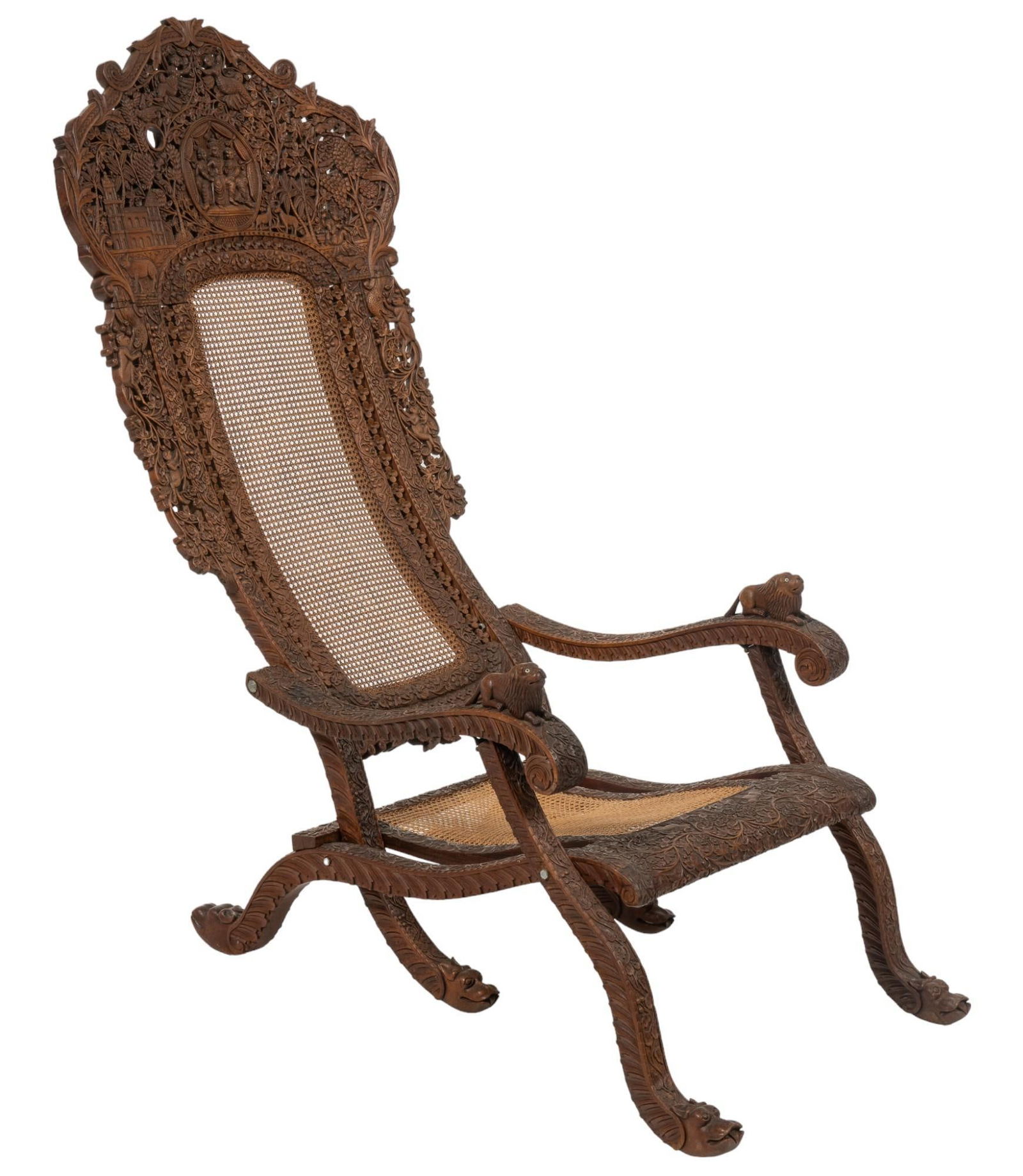 19th C. Carved Indian Cane Throne Chair: Indian decorative throne chair featuring highly intricate hand-carved wooden frame with scrolled floral, fauna, and figural motifs, framing cane backrest over cane seat, with armrests punctuated with