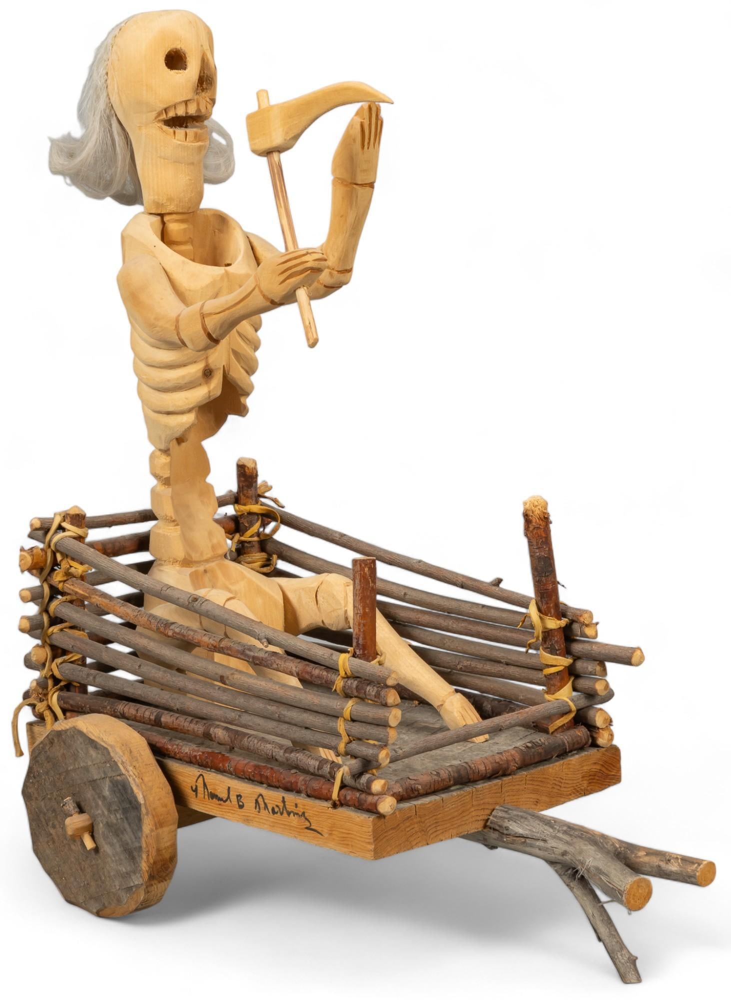 Manuel B. Martinez, Calle de Muerte Figure: Carved Mexican folk art piece, depicting calle de muerte (street of the dead) figure in car, with wooden twig and natural fiber accents, signed on side height 18.5 in. x width 10 in. x depth 16.5 in. 