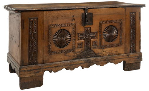 Carved Spanish Trunk: Wooden Spanish trunk featuring hinged lid opening to interior storage, above heavily carved facade with botanical and cross motifs, with large iron escutcheon, above carved apron height 34 in. x