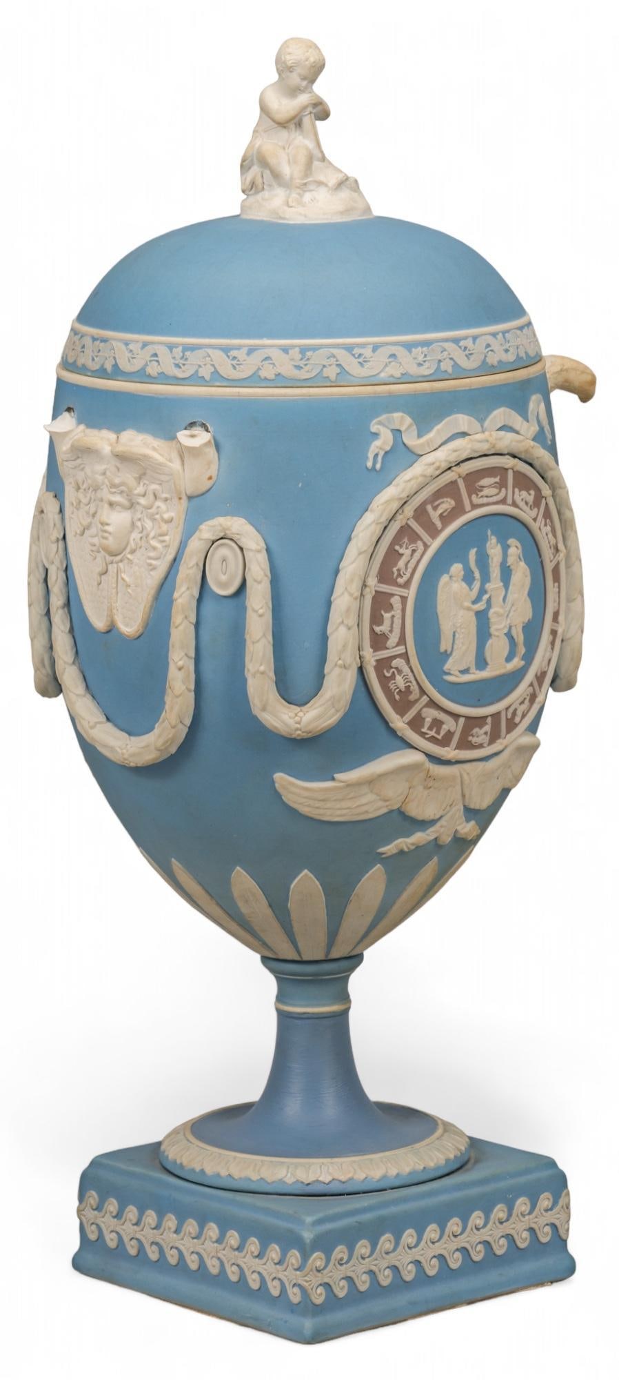 Wedgwood (ENG) Tricolor Jasperware Zodiac Covered Vase: Wedgwood (Stoke-On-Trent, England) tricolor jasperware covered vase, featuring pale blue surface, Neoclassical design with Medusa mask in white relief, gray Zodiac wheel, cherub finial height 14 in.