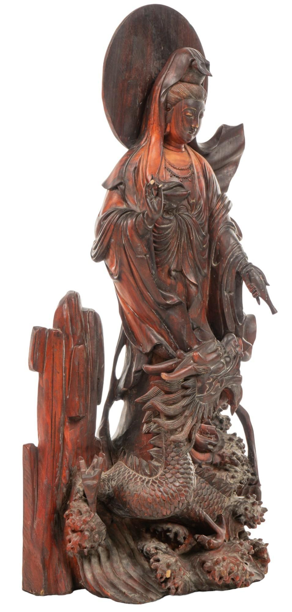 Chinese Guanyin Wooden Statue: Carved wooden Chinese sculpture depicting the Buddhist Bodhisattva Guanyin, adorned in robes and holding a water vase, with dragon and crashing waves height 38 in. x width 19 in. x depth 10.5 in. Cond