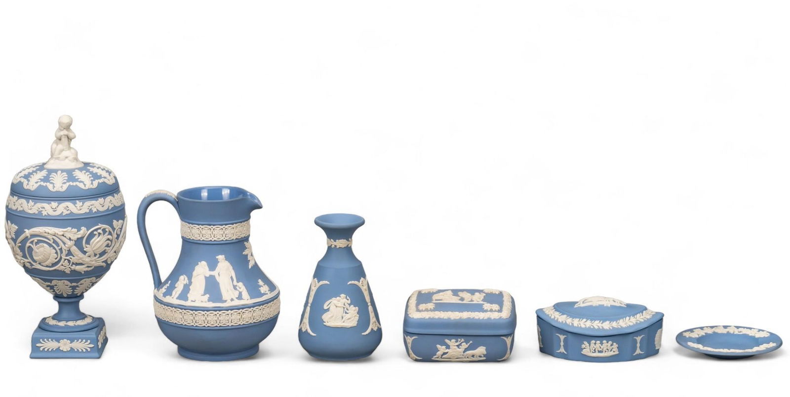 Collection of (6) Wedgwood (ENG) Pale Blue Jasperware: Collection of six Wedgwood (Stoke-On-Trent, England) pale blue jasperware, each having a Neoclassical design in relief, includes Arabesque vase with cherub fineal, Etruscan jug, vase, square lidded tr