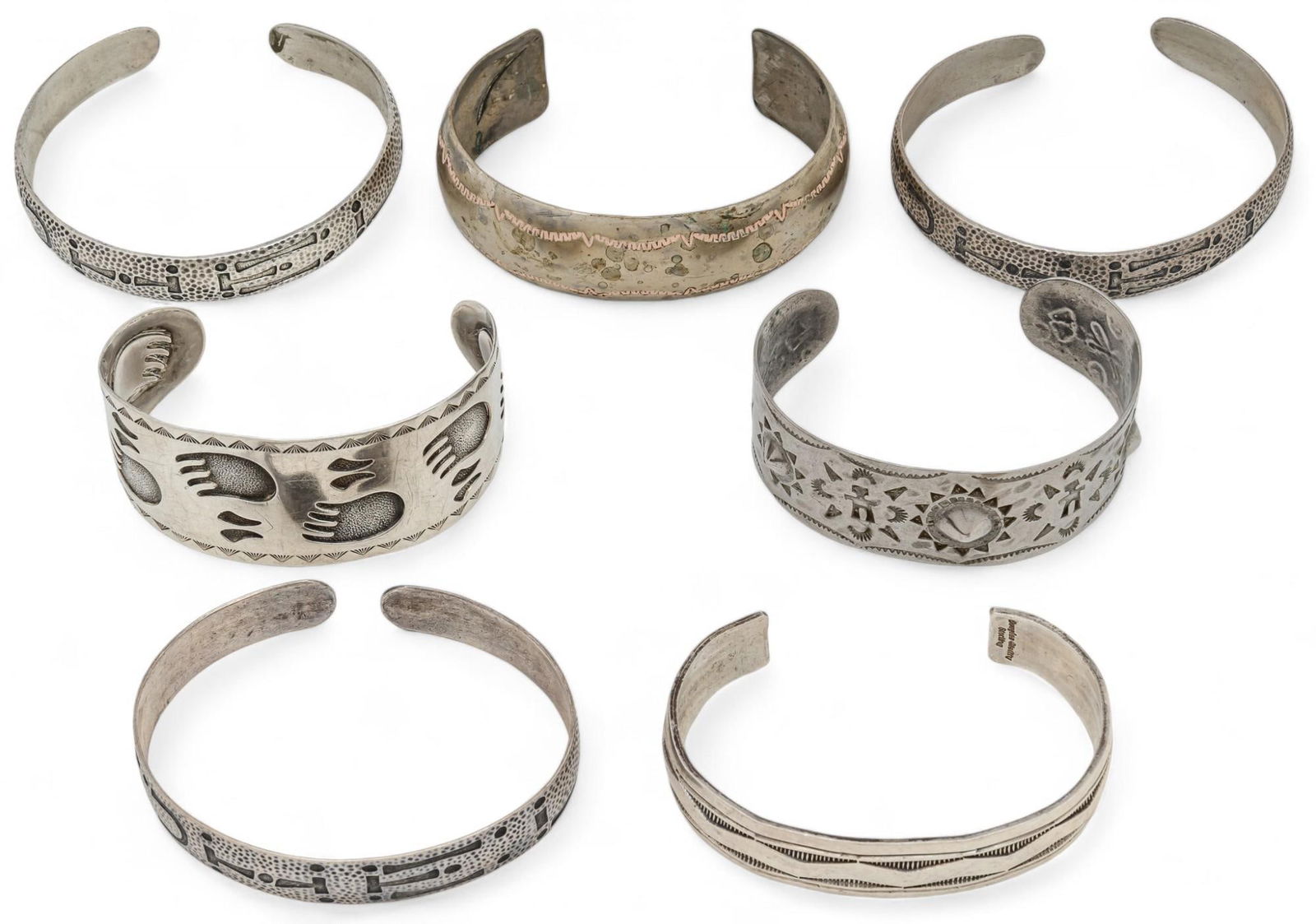 Set of (7) Sterling Silver Cuffs: Set of seven sterling silver cuffs includes three with geometric engraved motifs, one with paw print motifs, three with lettering engraving, six marked "Sterling", one unmarked Circumference: