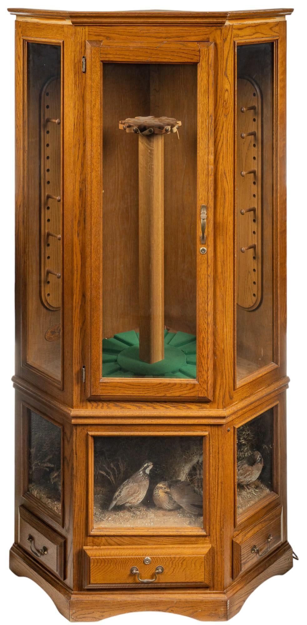 Gun Display Case With Taxidermy Quail Scene: Large column gun display case with taxidermy bird scene featuring central glass paneled gun display with locking door and key, with storage for twelve guns in addition to nine wooden pegs for hanging,