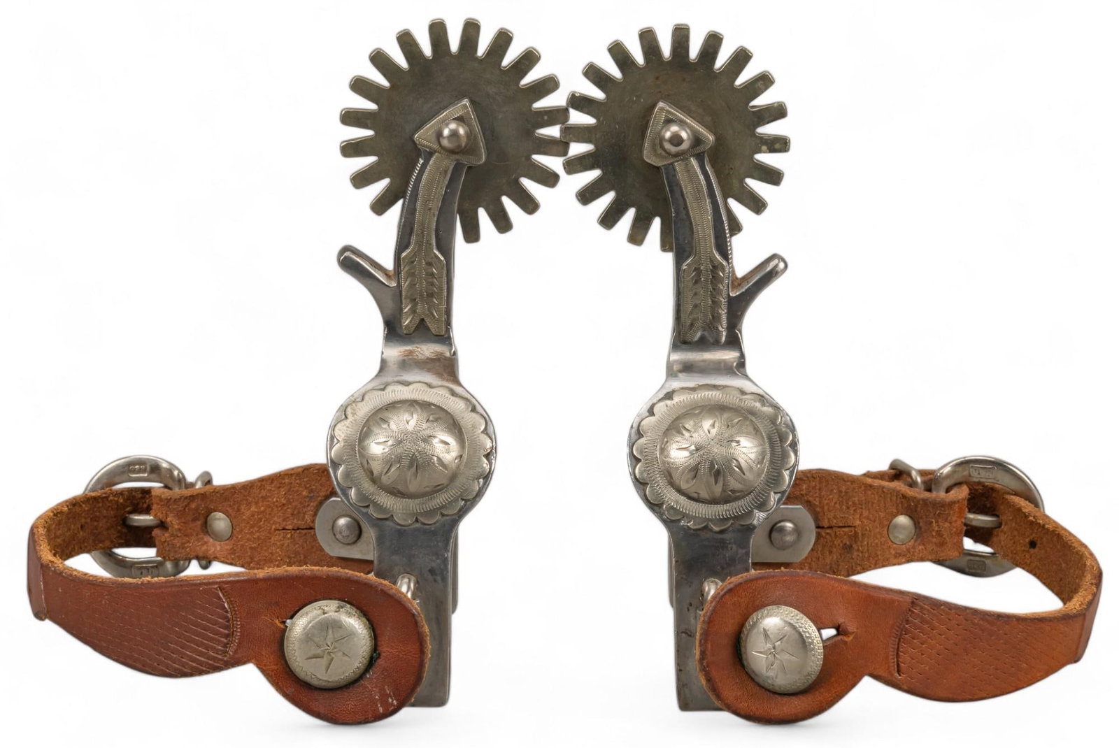 Pair of Arrow Shank Cowboy Spurs: Pair of arrow shank cowboy spurs featuring silver mounting detail on arrow shank, twenty rowel spurs, brown leather strap, unmarked, attributed to Crockett height 6.5 in. x width 4 in. x depth 2.25 in