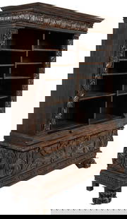 Renaissance Revival Bookcase: Renaissance Revival style bookcase, featuring carved molding above divided interior with four shelves on each side, above small extending tray with wooden pull, above heavily carved drawer that drops