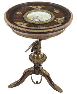 French Empire Style Porcelain Inset Gueridon: French empire style round gueridon featuring a porcelain inset of a mandolin courting scene under a glass surface, with a gilt metal decorative border and flying bird motif, atop a large metal eagle
