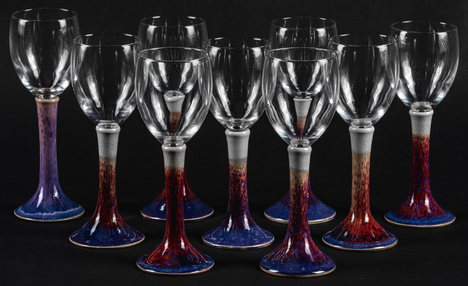 Set of (9) Ceramic Stemmed Glasses: Set of nine wine glasses with thick and colorful ceramic stems height 8.25 in. x width 3 in. x depth 3 in. Provenance: Property from the monumental lifetime collection of a distinguished Dallas, Texas