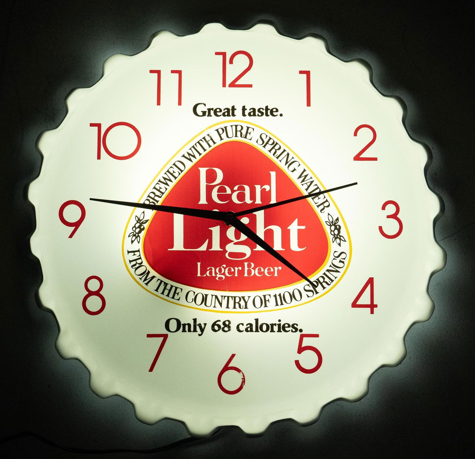 1980's Pearl Light Beer Lighted Wall Clock: Vintage Pearl Light Beer (San Antonio, Texas) lighted wall clock, featuring bottle cap shape, dated June 7th 1983, in working condition depth 3 in. x diameter 19 in. Provenance: Property from the