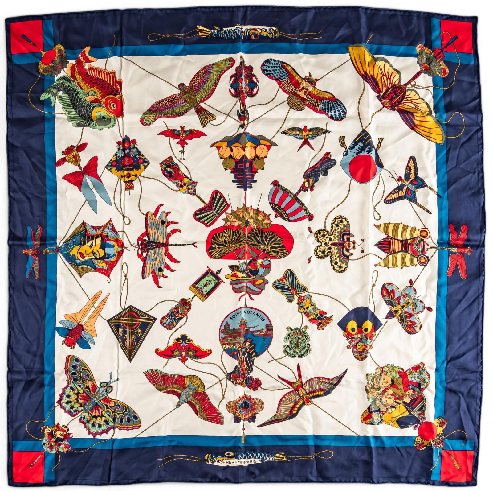 Hermes Soies Volantes Silk Scarf: Loic Dubigeon (France) designing for Hermes "Soies Volantes" (flying skies) silk scarf, white with graphic polychrome Asian silk kite motifs, with navy blue border punctuated with bright red c