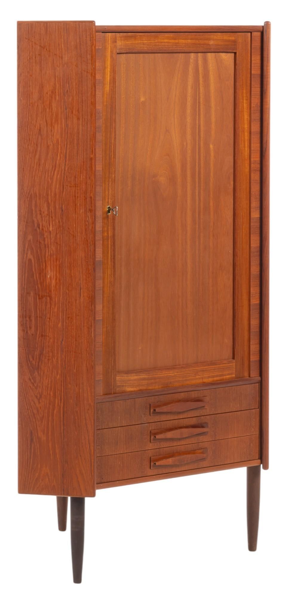Danish Mid-Century Corner Cabinet: Danish mid-century corner cabinet with door that opens to pair of shelves, and three bottom shelves, supported on pin legs height 57 in. x width 35 in. x depth 23 in.