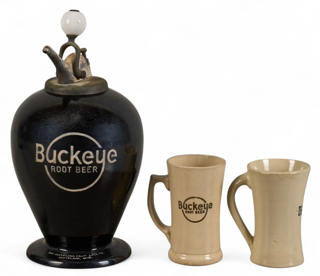 Buckeye Root Beer Syrup Dispenser and (2) Mugs: Vintage Buckeye root beer syrup dispenser, marked Cleveland Fruit Juice Co., with pair of matching mugs height 16 in. x diameter 8 in. / dispenser Provenance: Property from a home in San Antonio, Texa