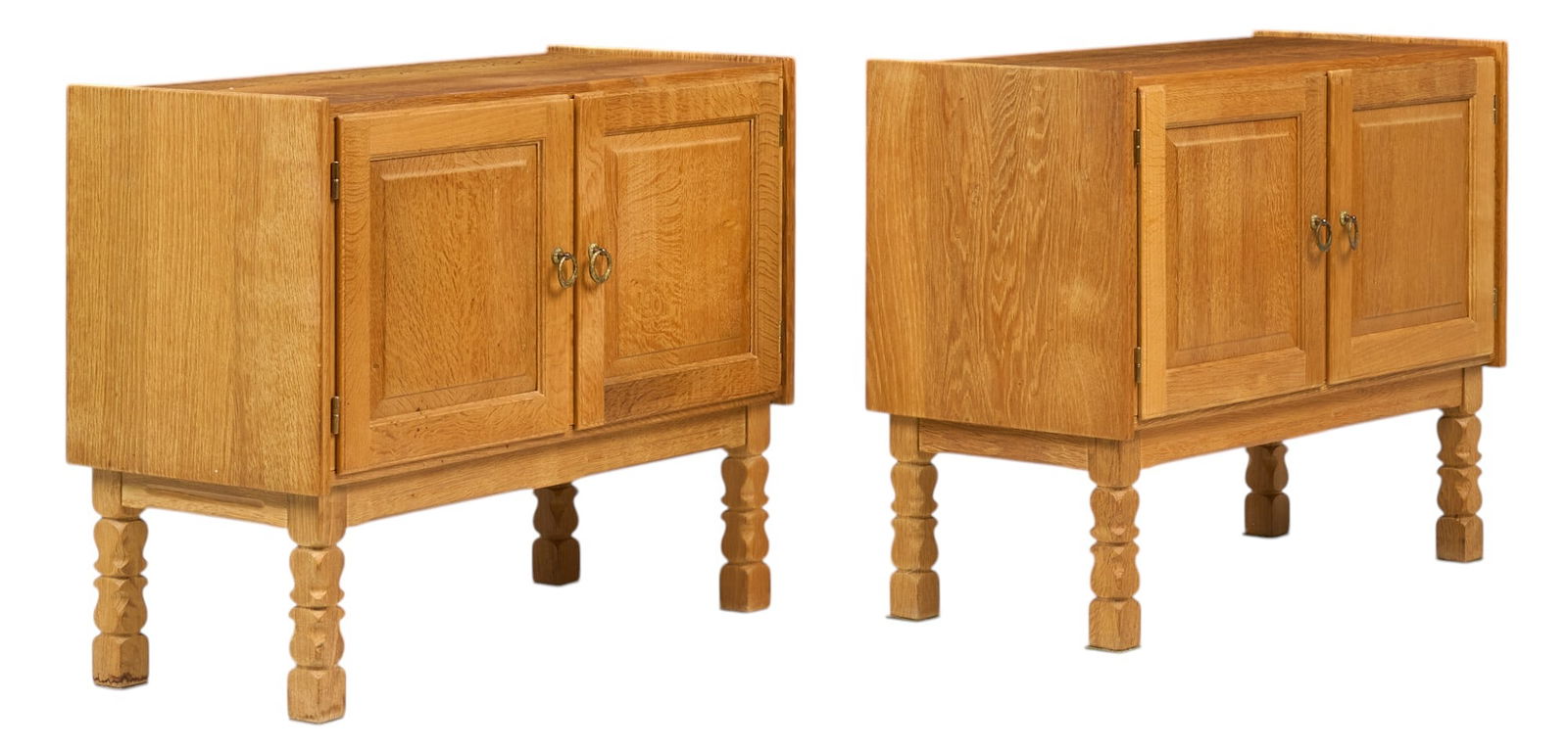 Pair of Henning Kjaernulf (DNK) Mid-Century Small Credenzas: Pair of Henning Kjaernulf (DNK) mid-century small oak credenzas featuring two hinged doors opening to interior storage space with two shelves, carved details on doors, metal pulls, on carved block leg