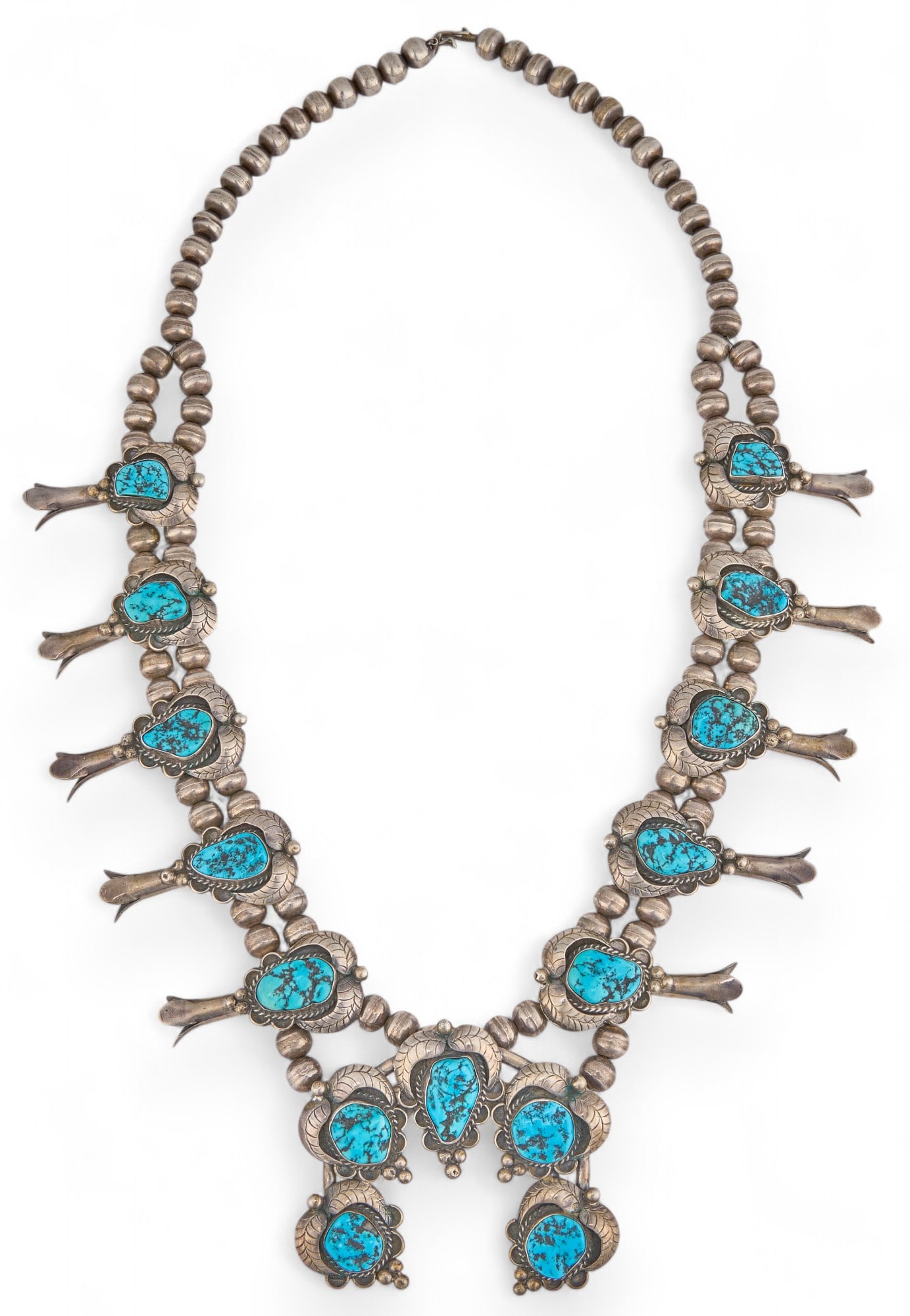 Sterling Silver and Turquoise Squash Blossom: Sterling silver squash blossom with turquoise inlay, and botanical motifs length 26 in. total weight: 5.15 ozt Provenance: Property from a home in San Antonio, Texas