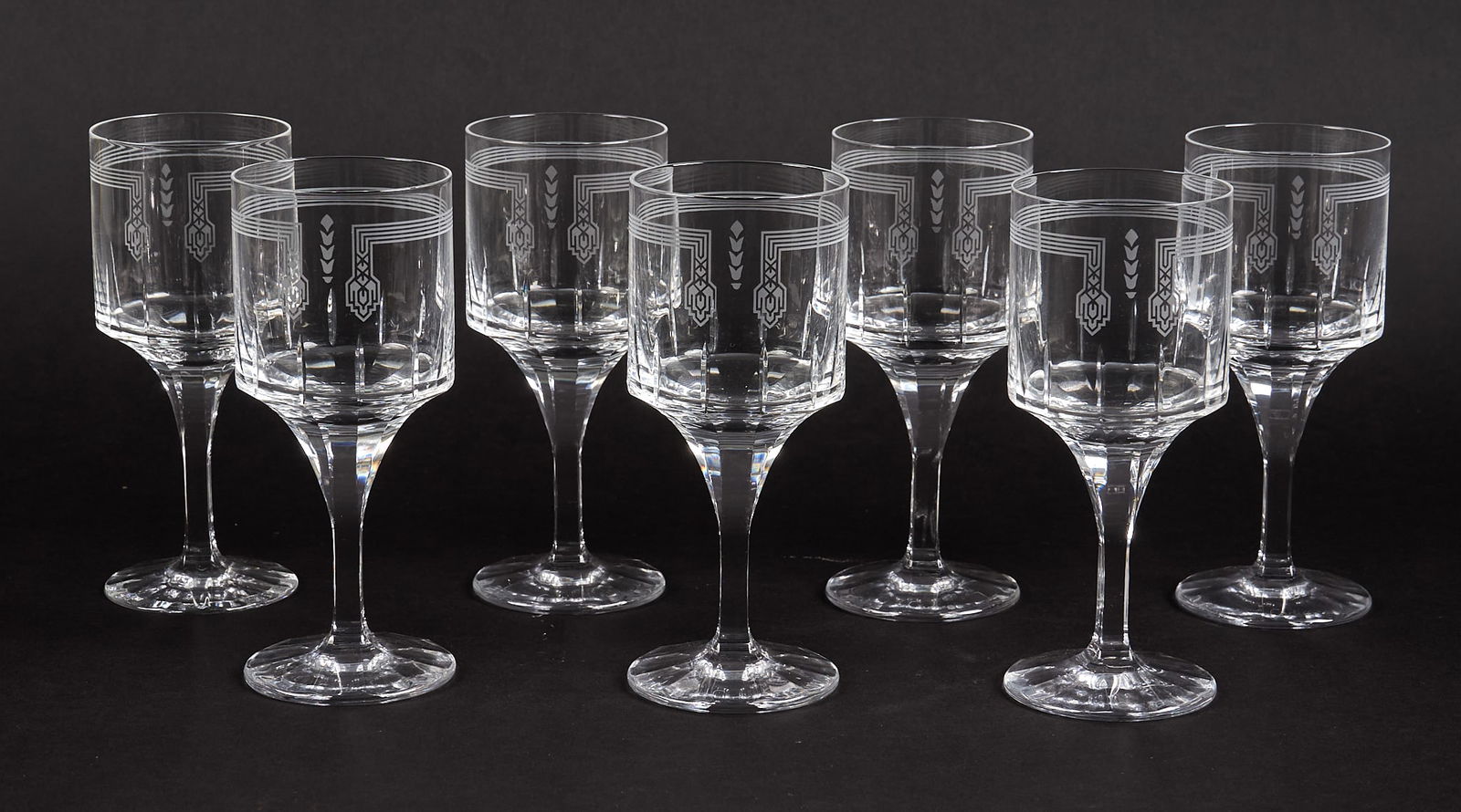 (7) Cartier "Des Ballets Russes" Crystal Wine Goblets: Set of seven Cartier "Des Ballets Russes" crystal wine goblets, each with a cylindrical bowl engraved with stylized Art Deco drapery and pendant motifs, tapered stems terminating in circular
