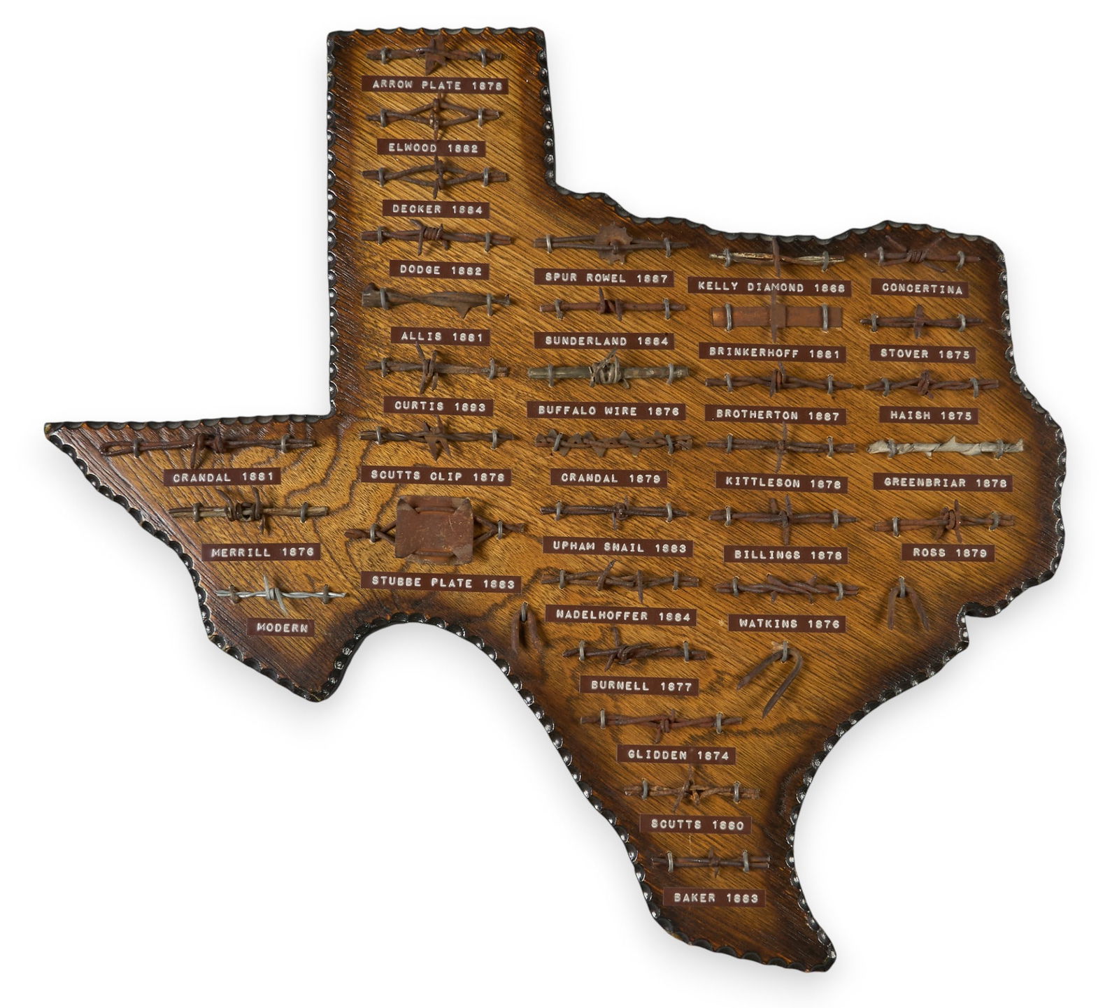 Texas Barbed Wire Display: Vintage barbed wire wall display, wooden form in the shape of the state of Texas, with different barbed wire, each labeled and datedheight 21 in. x width 22 in. x depth 1 in.Provenance: Property from