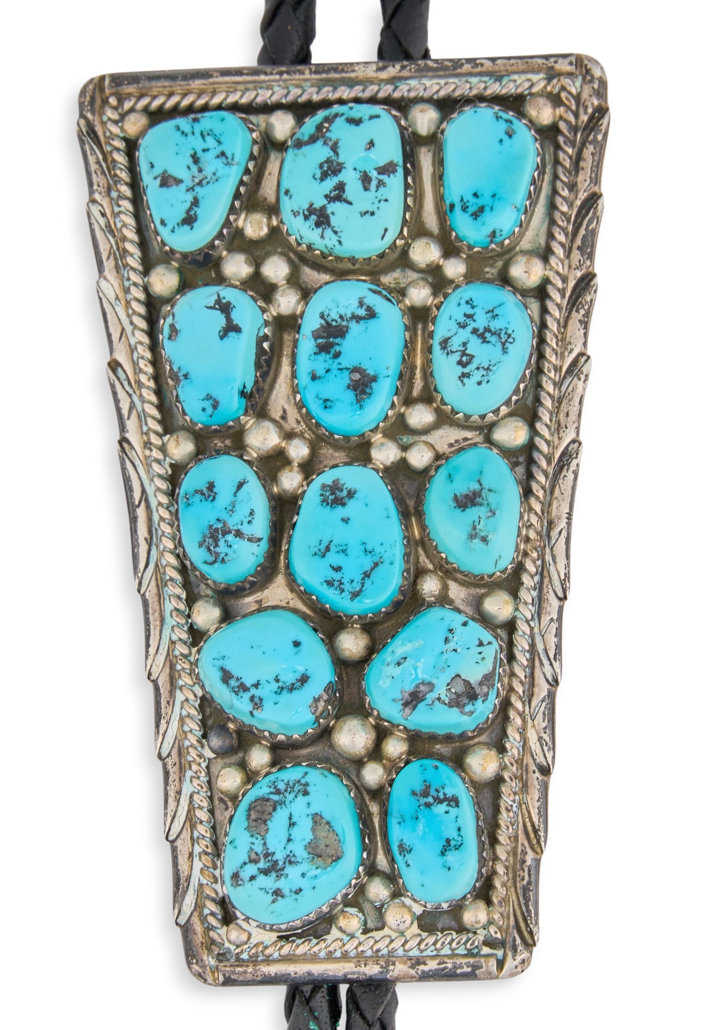 Turquoise Cluster Bolo Tie: Native American bolo tie, with turquoise cluster inlay and twisted rope details, on braided black leather Length: 45 in.Pendant: 3 x 1.75 in.Total weight: 1.665 ozt Provenance: Property from a home in