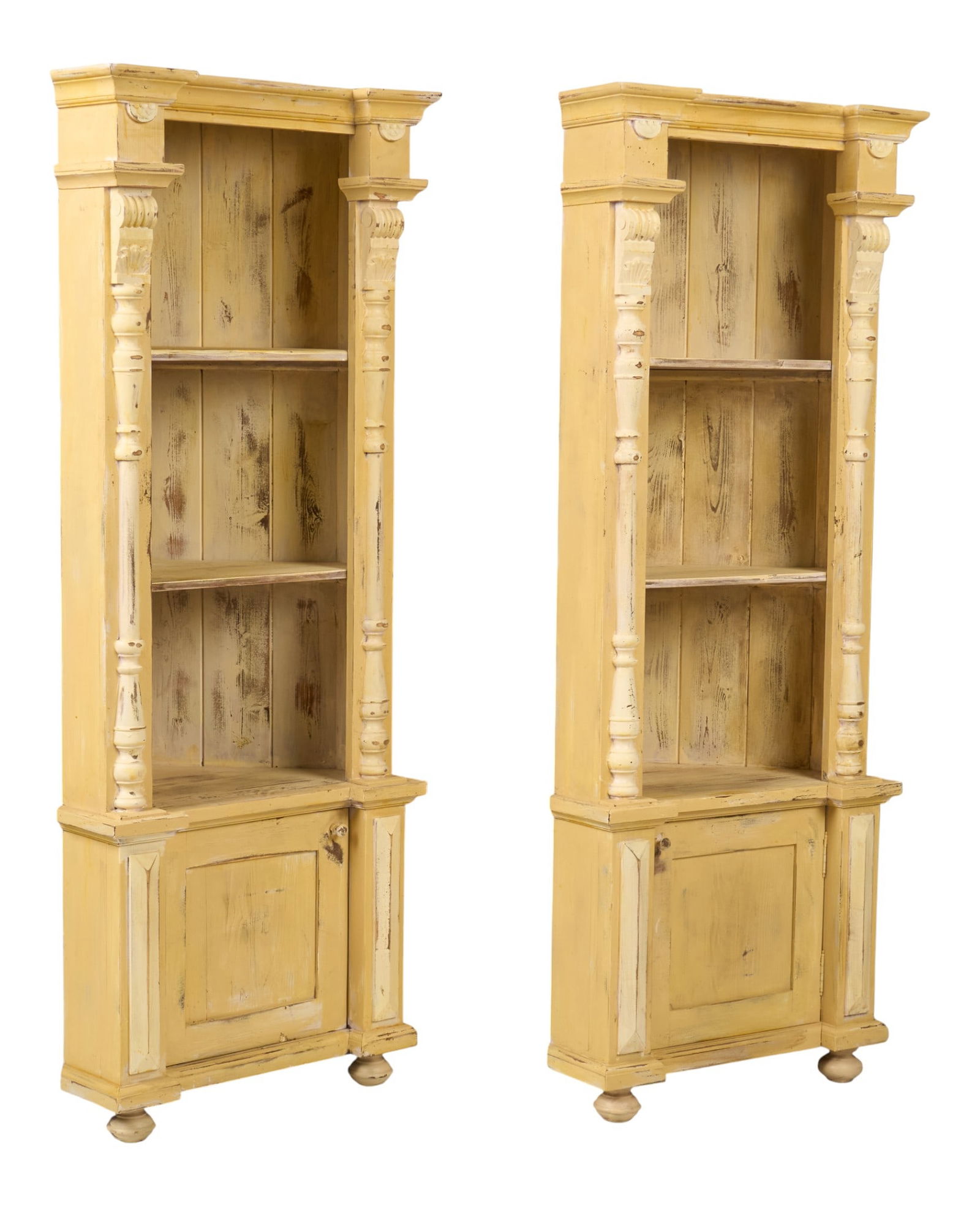 Pair of Rustic Corner Bookcases: Pair of rustic corner bookcases with two shelves, and bottom cabinets, supported on bun feet, with distressed yellow paint finish height 75 in. x width 28 in. x depth 22 in. / each