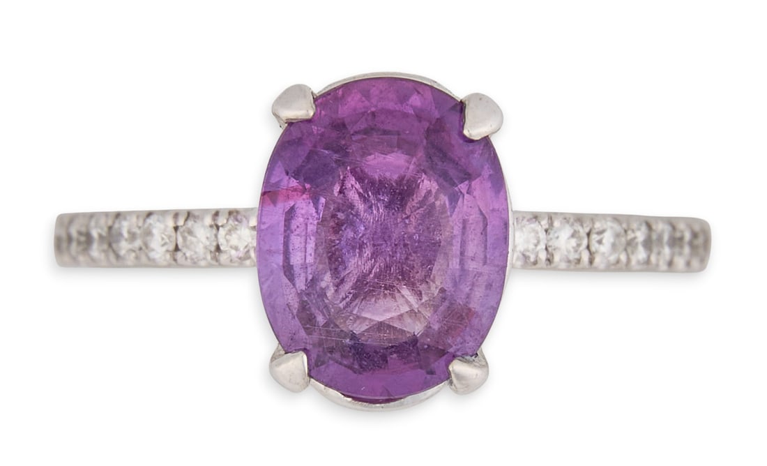14K Purple-Pink Sapphire & Diamond Ring: 14K white gold ring, set with an oval-cut purple-pink sapphire weighing approximately 1.93 ct, flanked by round brilliant-cut diamonds set along the band totaling approximately 0.23 ctw, marked