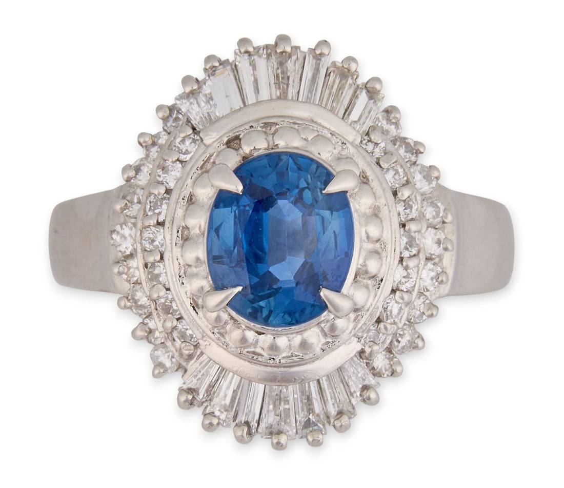 Platinum Sapphire & Diamond Halo Ring: Platinum ring set with a central oval cut sapphire (approx 1.47 ct), surrounded by a halo of round and baguette cut diamond accents (approx 0.63 ctw), marked "Pt 900" Size: 6.5Total weight: