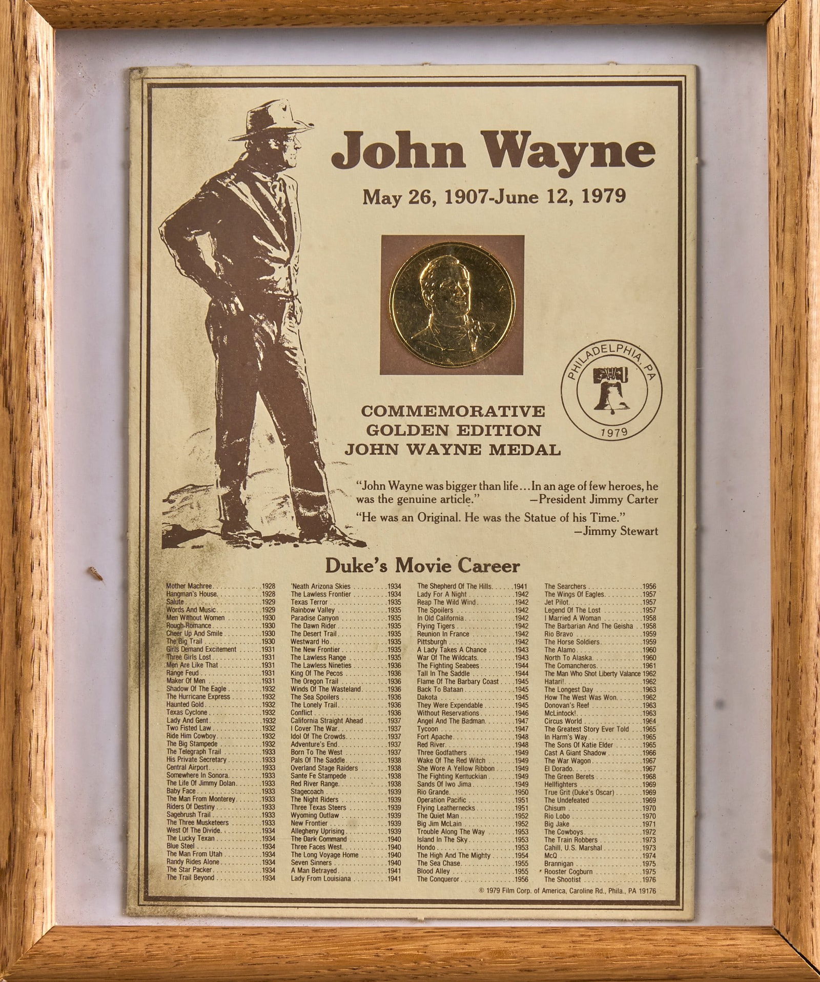 Commemorative John Wayne Medal: Framed John Wayne commemorative golden edition medal presented with paper material listing John Wayne's filmographyheight 13 in. x width 11.25 in. x depth 3 in. Provenance: Property from a