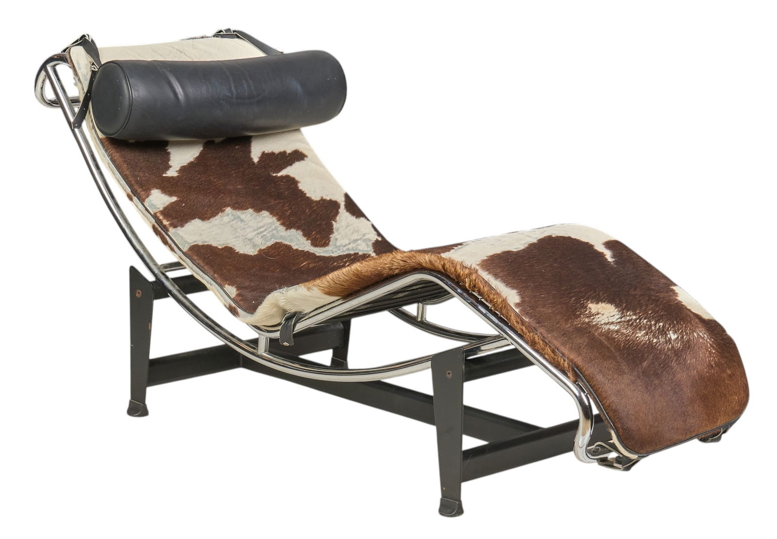 After Le Corbusier Chaise Lounge Chair: Mid-century lounge chair, chrome frame with cowhide upholstery, and black leather pillow, supported on black base, after an original 1928 design by Charles-Édouard Jeanneret (Swit.,
