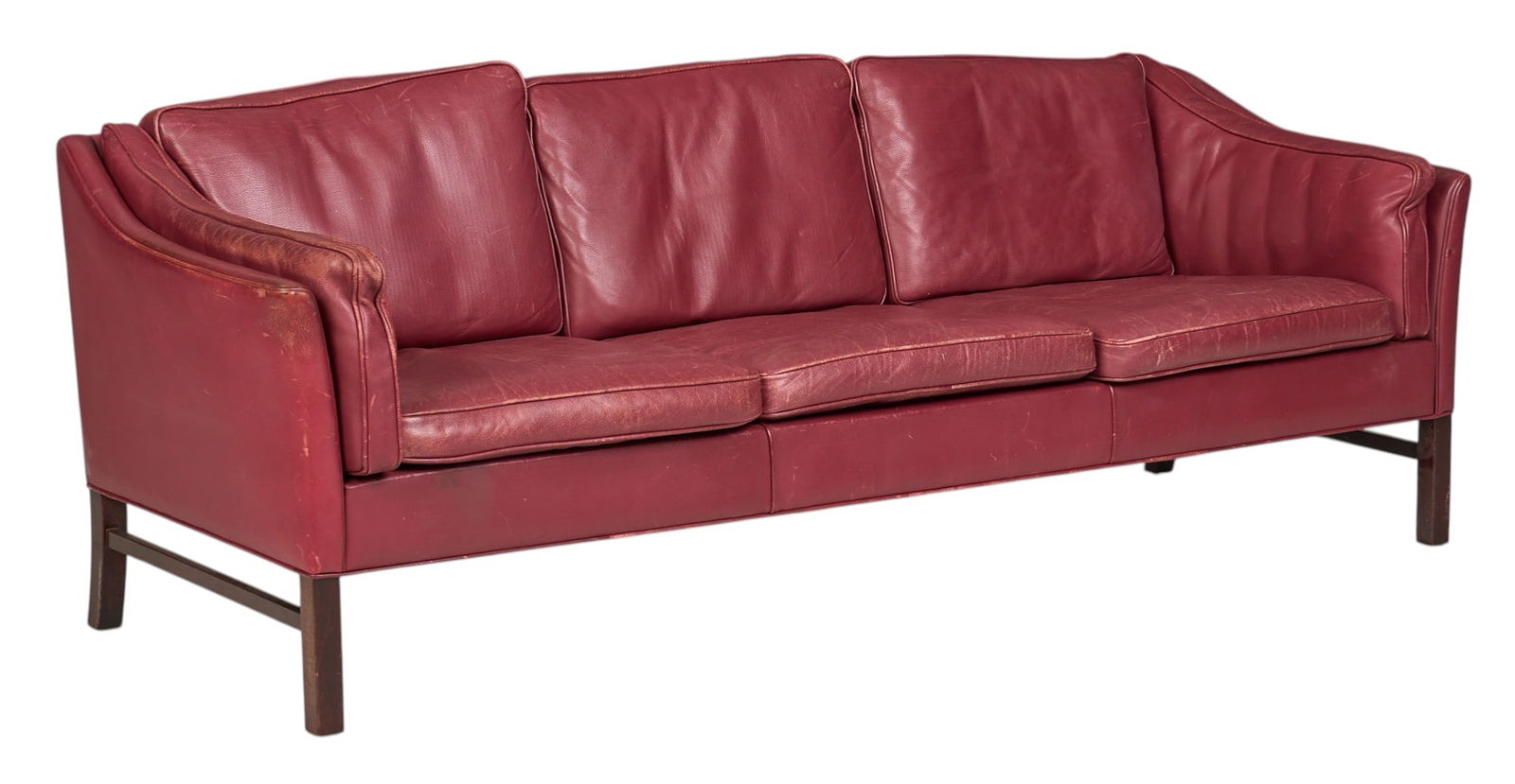 Danish Mid-Century Leather Sofa: Danish mid-century sofa with oxblood leather upholstery and removable cushions, supported on block legs height 27.5 in. x width 80 in. x depth 29 in. Condition: Some discoloration to l