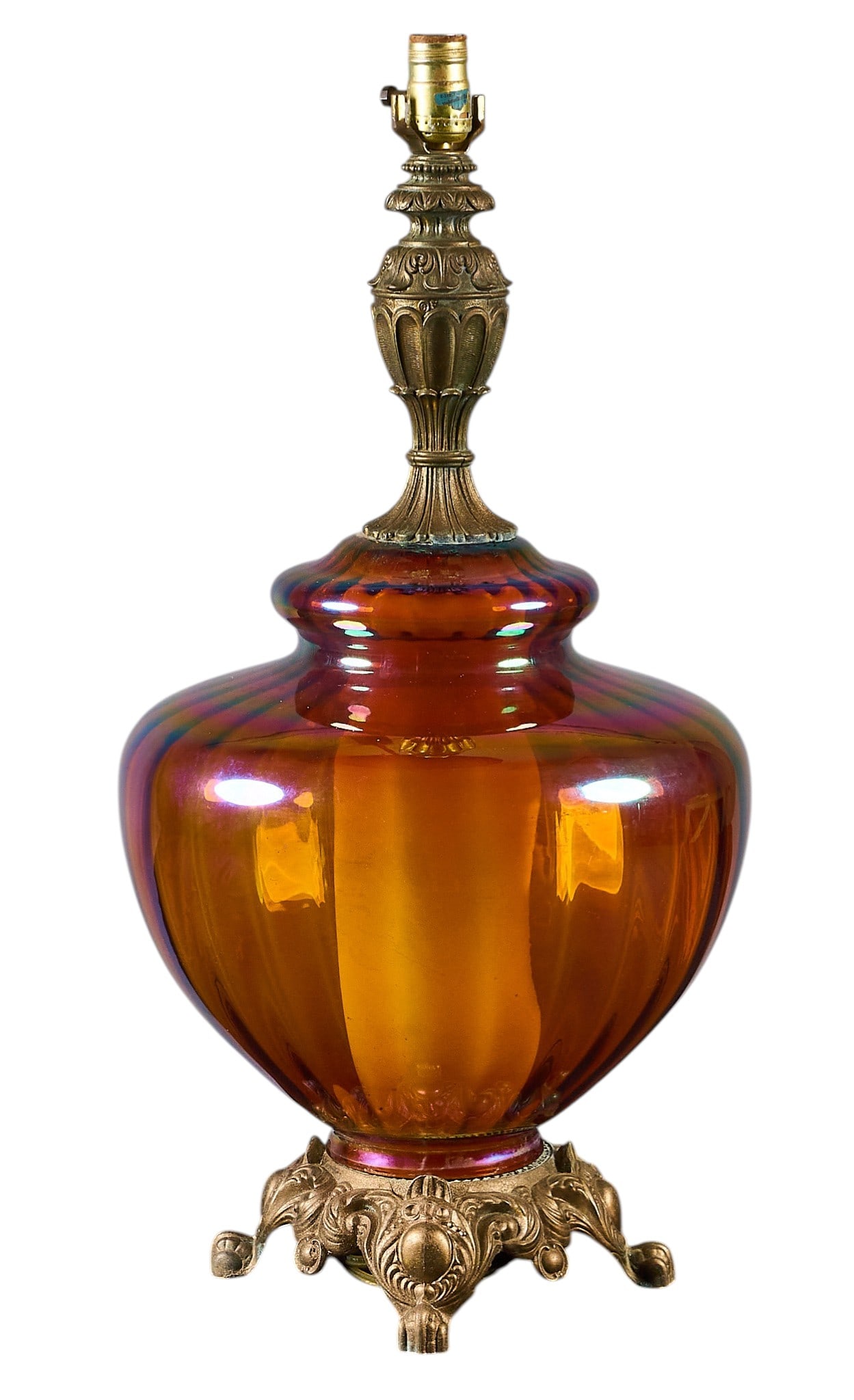 Mid-Century Glass Lamp: Mid-century lamp featuring an amber colored iridescent glass body and an ornate cast metal base and finial height 28 in. x diameter 14 in. Provenance: Property from a home in Bulverde, Texas