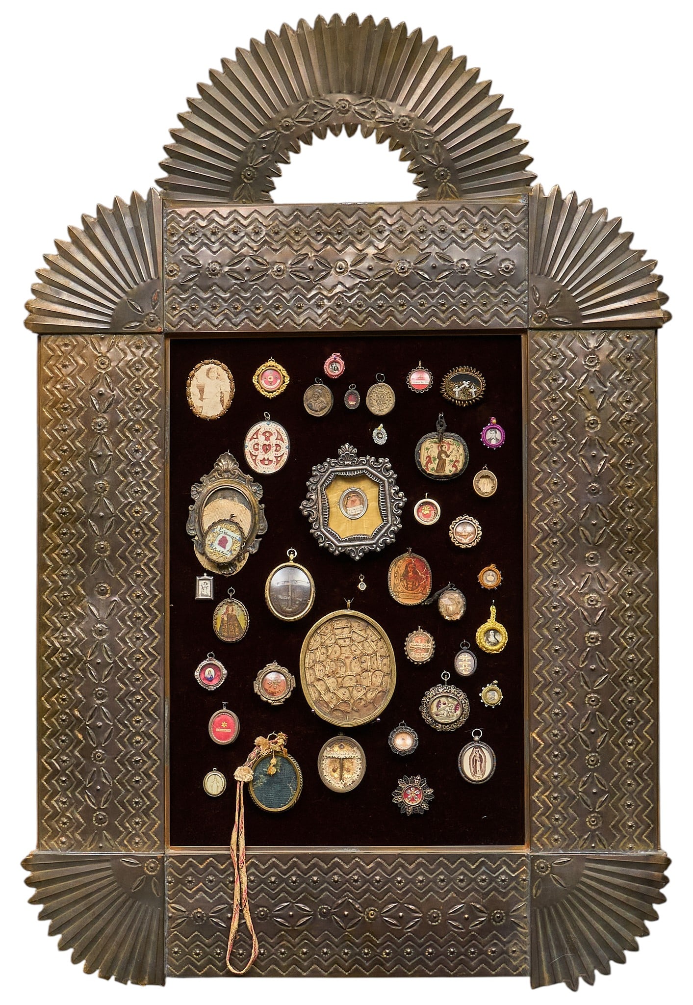 Framed Milagros and Photo Medallion Display: Framed display of milagros prayer charms, religious photo medallions, in hand-tooled tin frame height 37 in. x width 25 in. x depth 1 in. Provenance: The Estate collection of late teacher and humanita