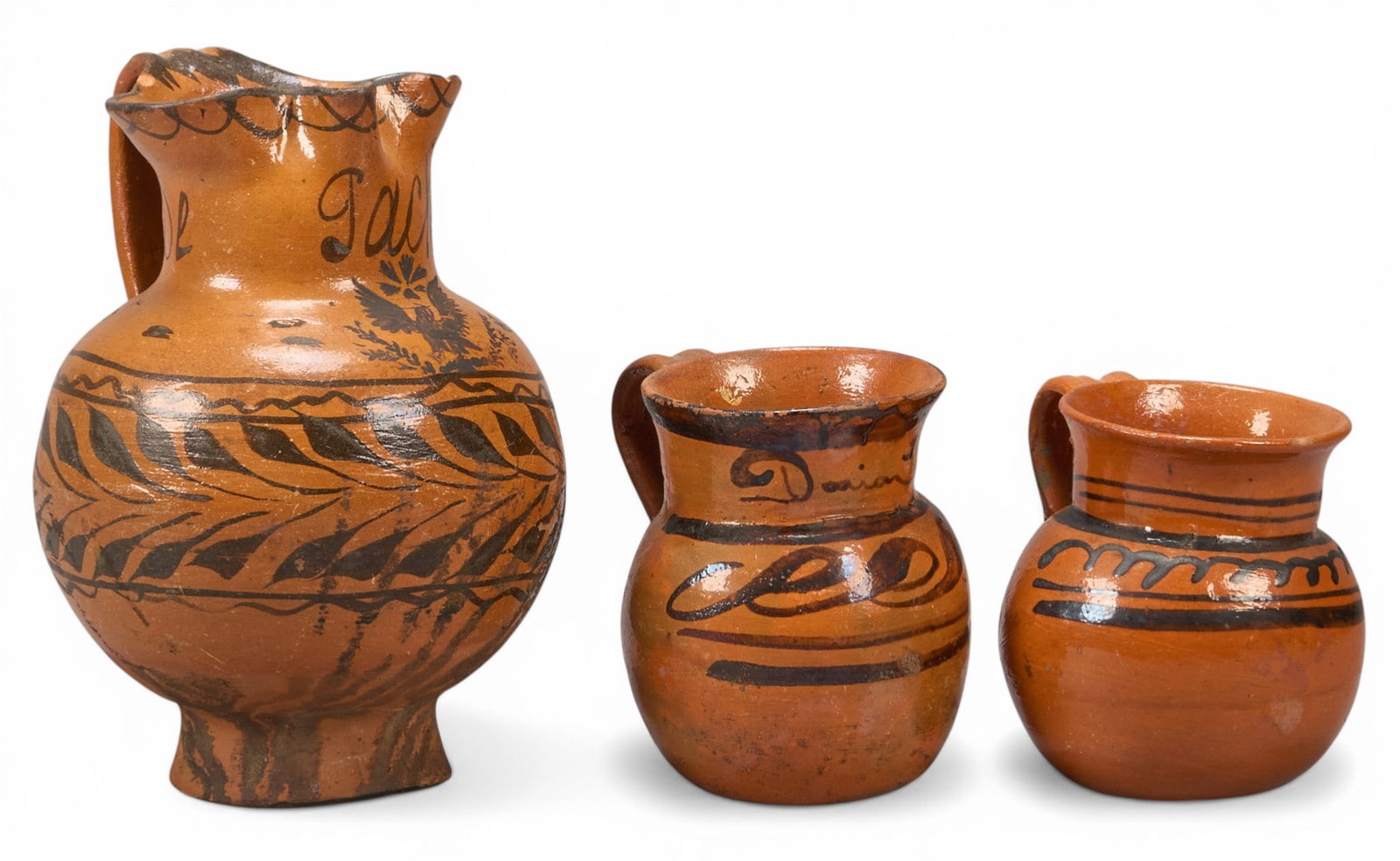 Vintage Mexcan Earthenware Pitcher and Mugs: Vintage Mexican earthenware pitcher and two cups with handles and bulbous forms, circa 20th century height 9 in. x width 6.5 in. x depth 6.5 in. / pitcher Provenance: The Estate collection of late tea