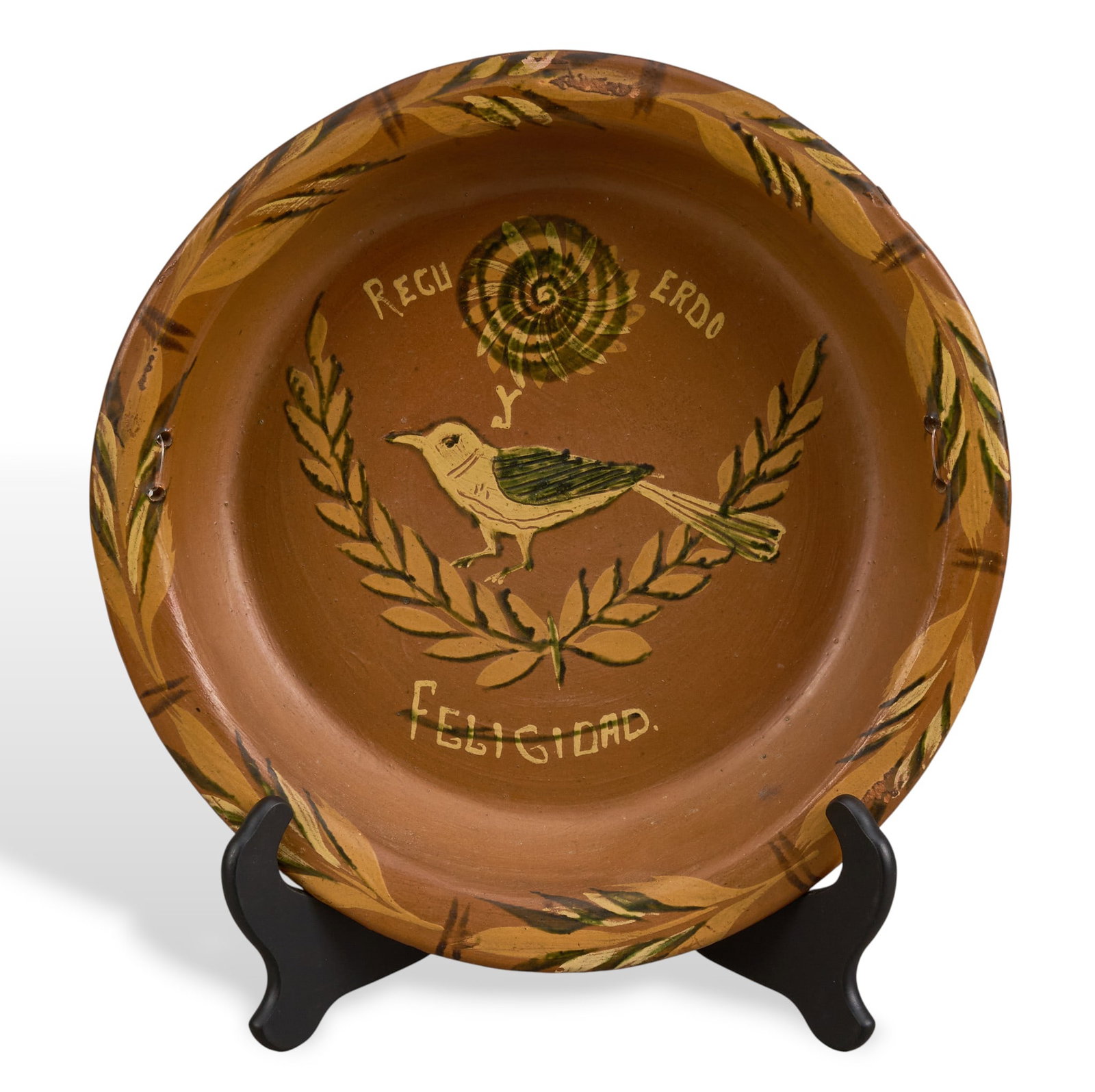 Mexican Pottery Dish with Bird Motif: Mexican pottery dish featuring a bird perched on a laurel branch, with the words "Recuerdo y Felicidad."diameter 14.5 in. x depth 2.25 in.Provenance: Property from a home in Rockport, Texas
