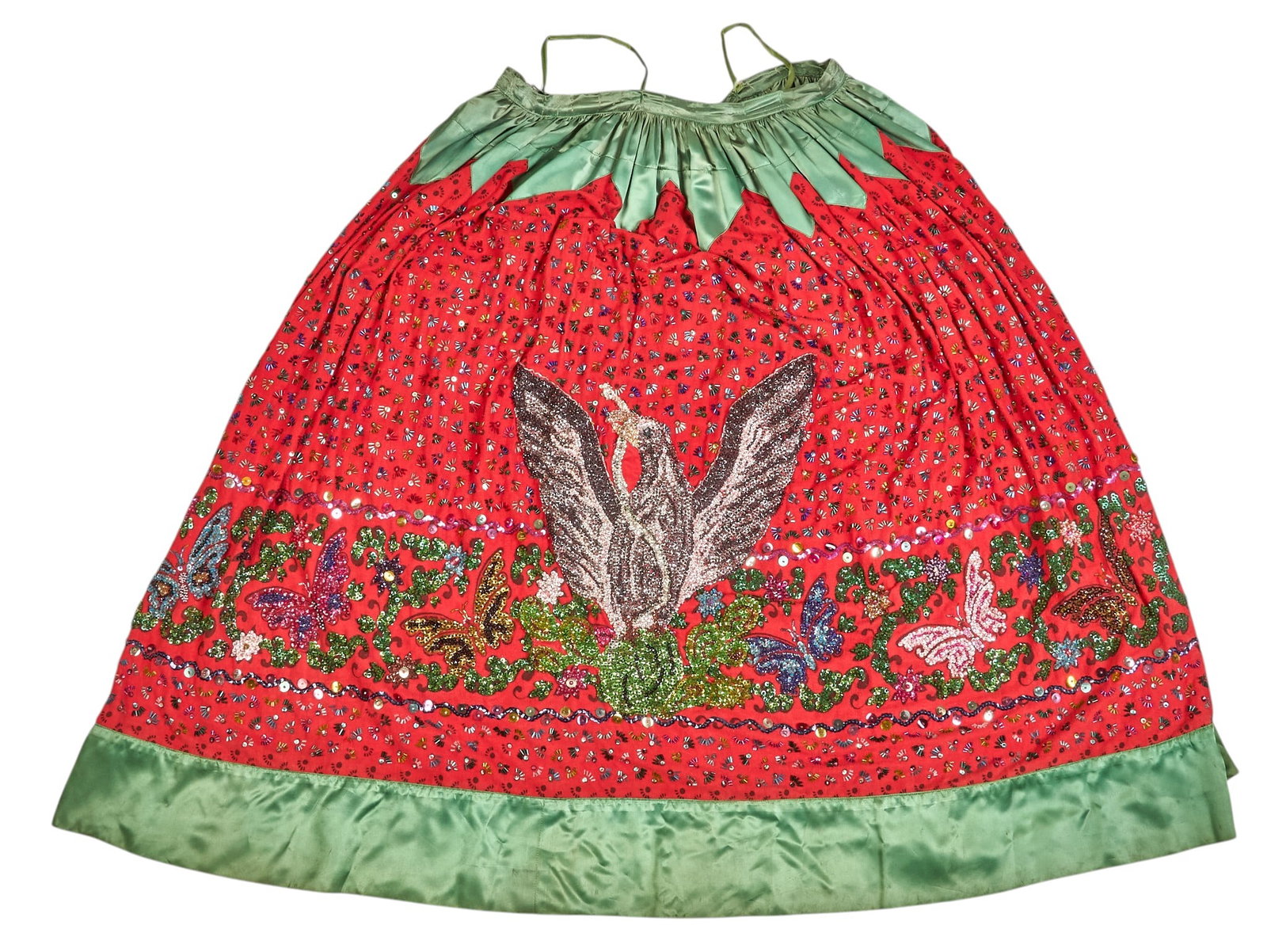 Vintage Mexican China Poblano Skirt: Vintage Mexican china poblano dancing skirt of red fabric and green satin trim, with numerous hand-sewn glass beads arranged in floral motifs, and depicting Mexican Coat of Arms, with two hook cl