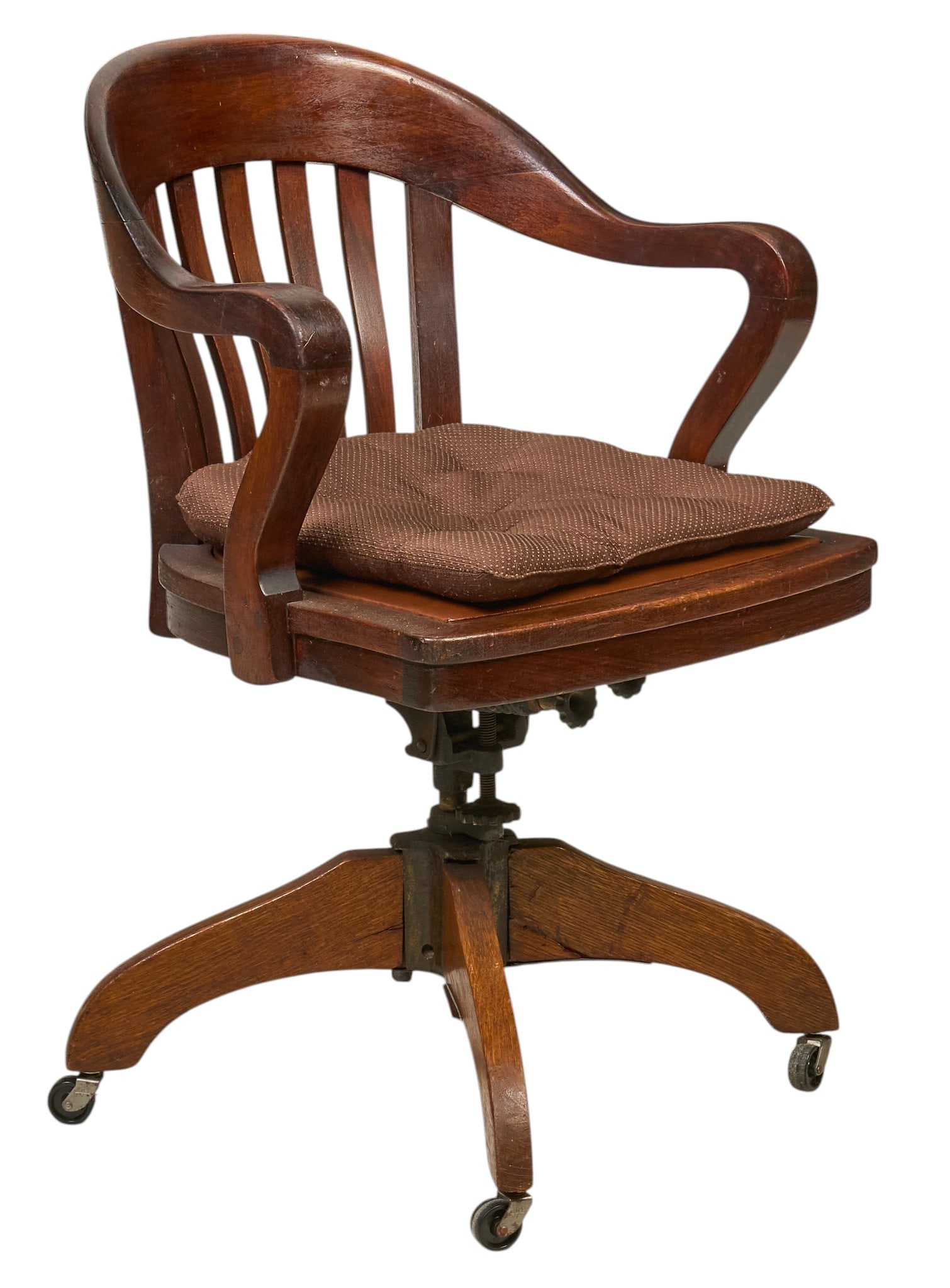 Barrel Back Rolling Chair: Wooden rolling chair with a curved back, slatted backrest, and brown upholstered seat cushion, on four legs ending in casters height 35 in. x width 23.5 in. x depth 24.5 in. Provenance: Property