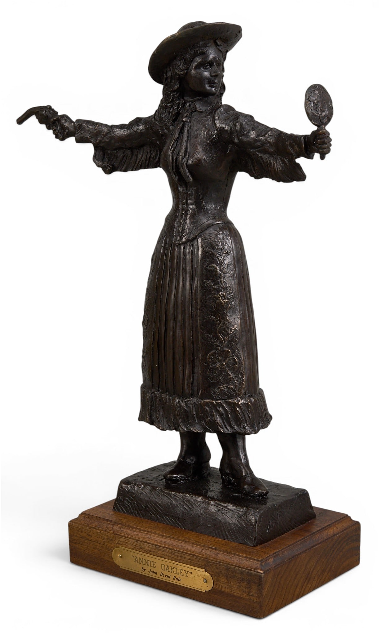 John David Rule, "Annie Oakley": John David Rule (Amer., 20th-21st C.), "Annie Oakley", artist-cast bronze sculpture on wooden base, incised signature and title height 17.5 in. x width 13 in. x depth 5.75 in.
