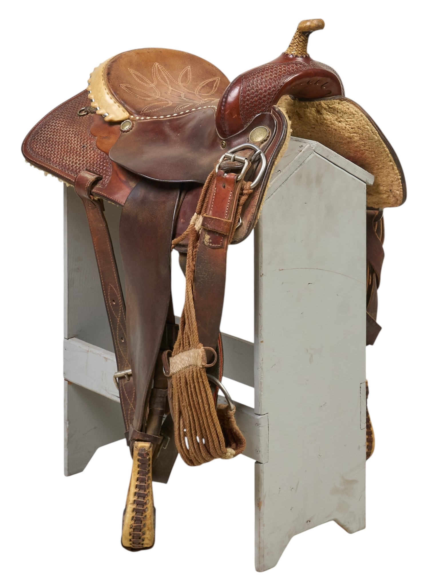 Circle Y Western Saddle: Circle-Y western saddle, hand-made with intricate tooling and decorative metal conchos, with a padded seat, leather stirrups, and fringed accents, marked height 39 in. x width 26 in. x depth 22 i