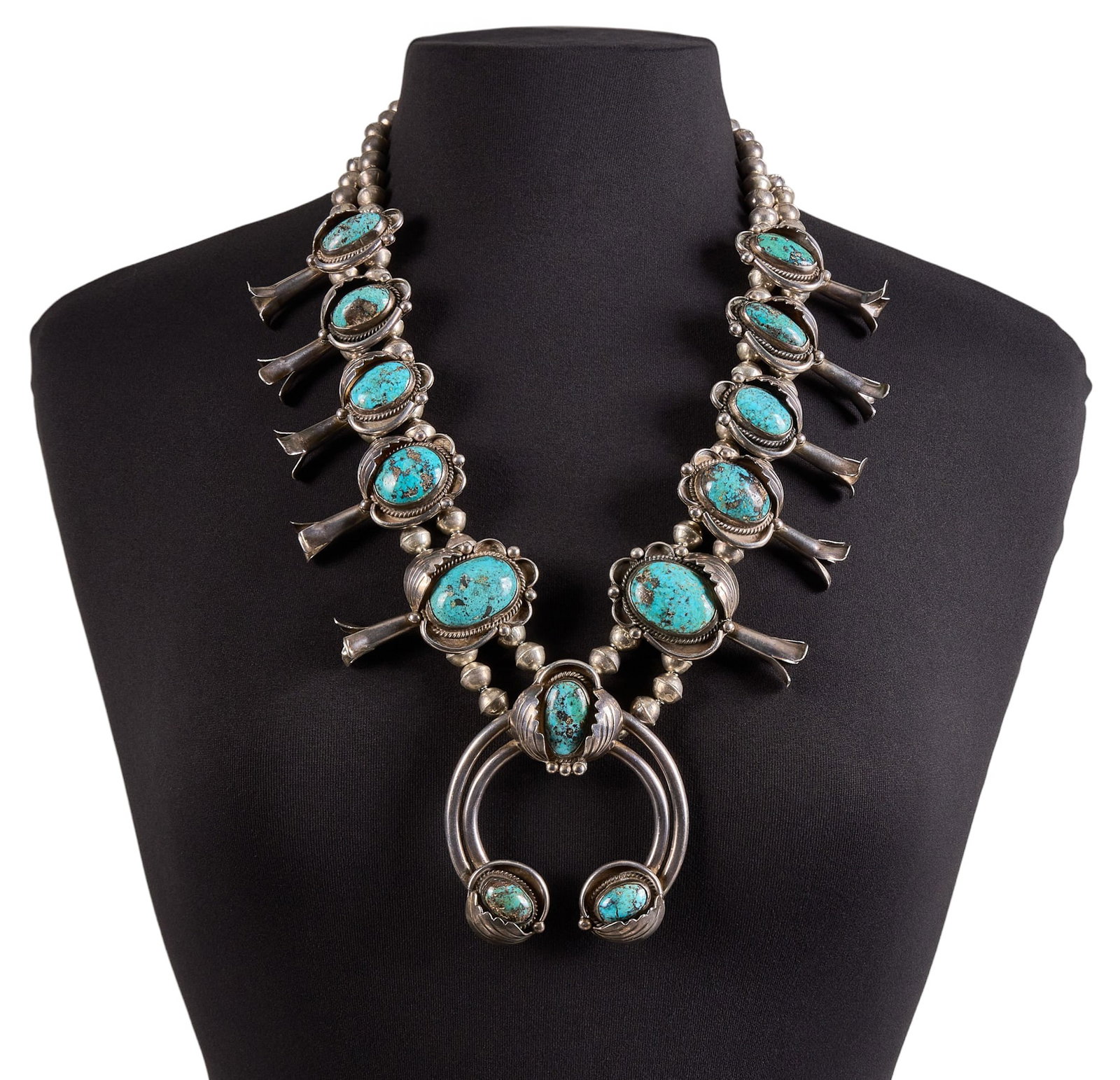 Navajo Sterling Silver & Turquoise Squash Blossom: Navajo sterling silver squash blossom necklace, set with large turquoise cabochons, featuring twisted rope and leaf motifs, and hook and eye closure, marked to naja Length: 28 in. Total weight: 3