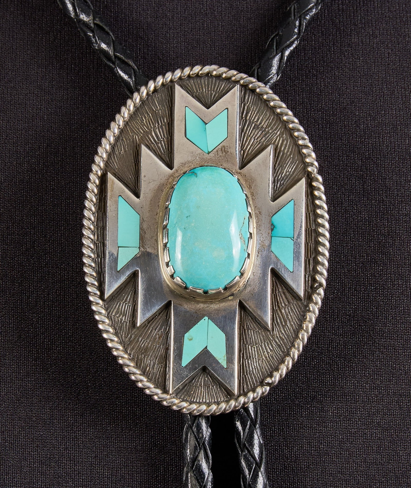 Steve Gunyon, Vintage Sterling Silver & Turquoise Bolo: Steve Gunyon (Yakima), vintage sterling silver bolo tie, set with turquoise cabochon and inlay, featuring twisted rope motif throughout, on braided black leather cord, signed "SJG" and dated