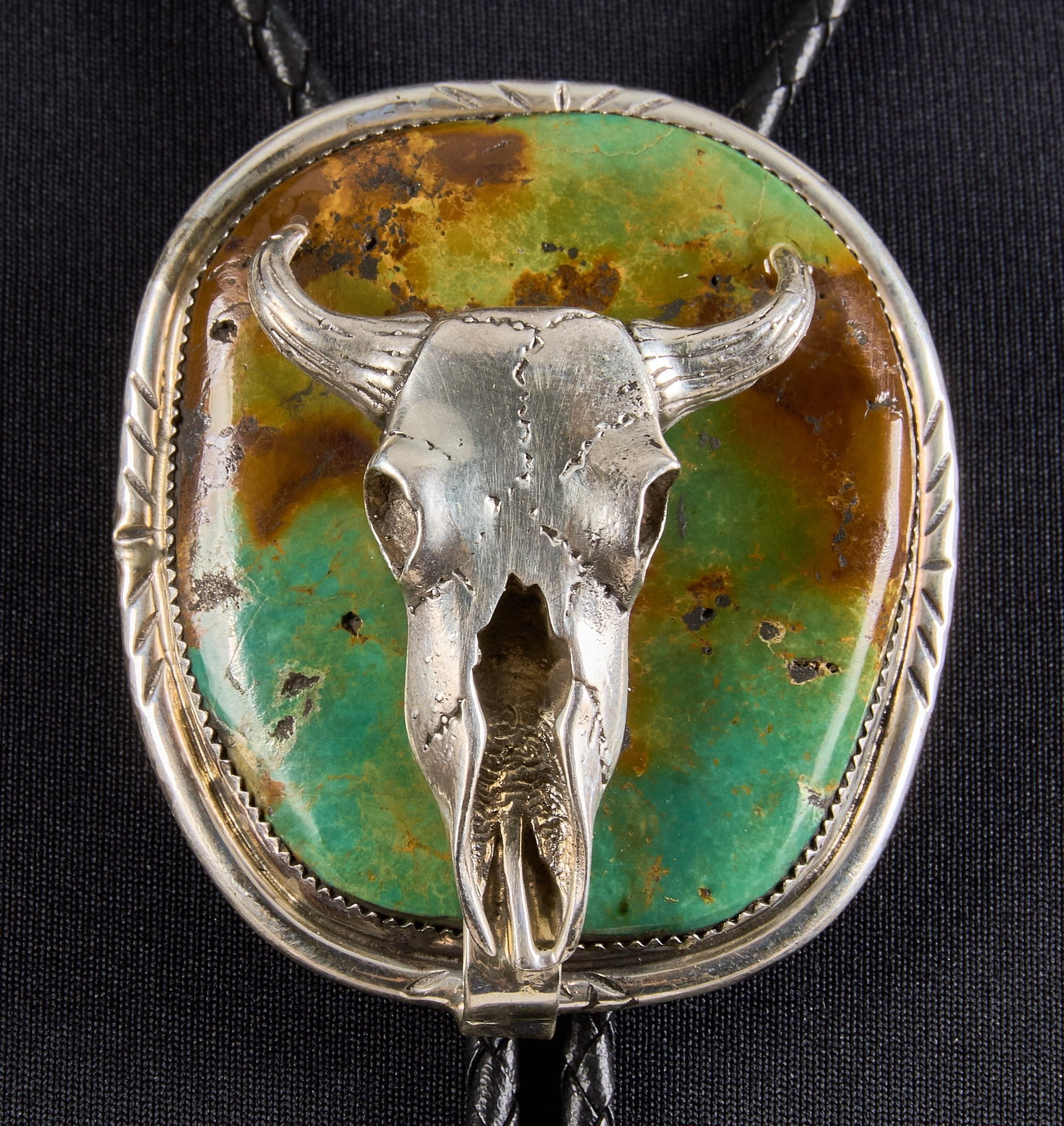 Sterling & Turquoise Steer Horn Skull Bolo Tie: Sterling silver bolo tie, set with large turquoise stone and steer horn skull motif, on braided black leather cord, marked "J Sterling" Length: 39 in. Total weight: 90.3 g Provenance: Proper