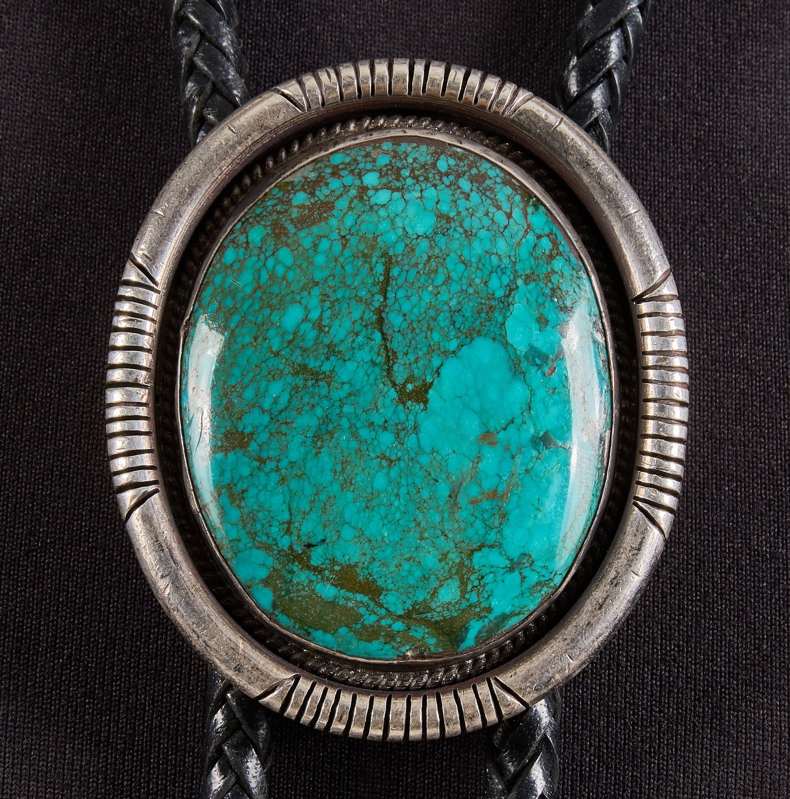 Southwestern Sterling Silver & Turquoise Bolo: Southwestern sterling silver bolo tie, set with large turquoise cabochon and featuring stamped details to border, on braided black leather cord, signed "John Renner Sterling" Length: 48 