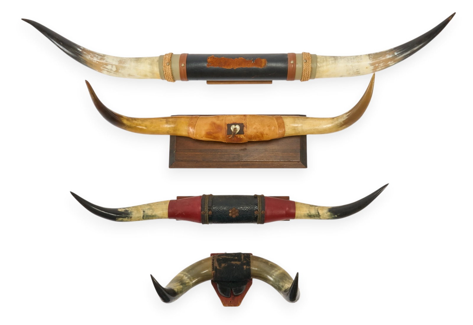 (4) Mounted Longhorn Skulls and Horns: Collection of four mounted longhorn skulls and horns, with decorative bands and wooden mounts height 38 in. x width 59.5 in. Provenance: Property from a home in Weatherford, Texas