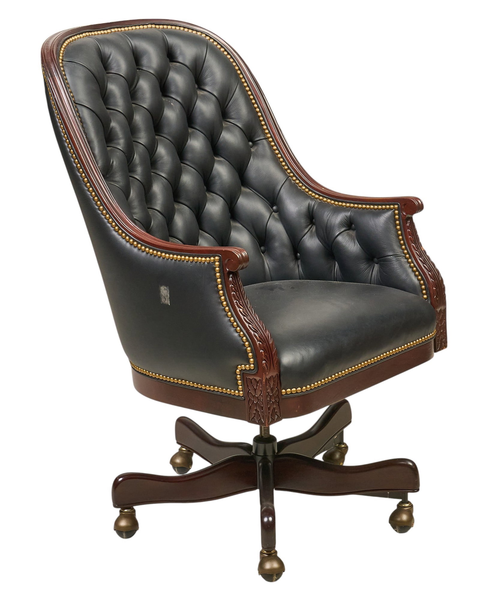 Tufted Leather Executive Swivel Chair: Executive swivel chair upholstered in black tufted leather with ornate carved wooden accents on the arms and base, brass nailhead trim, and a five-star base with casters height 44 in.&n
