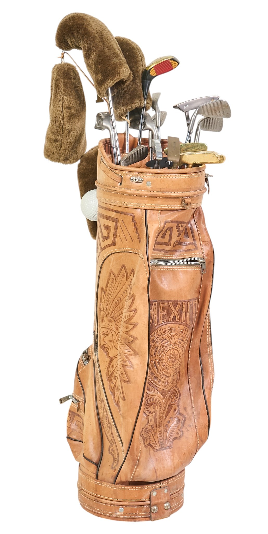 Vintage Carved Leather Golf Bag with Clubs and Covers: Vintage golf set with intricately carved leather golf bag with "MEXICO" embossed on the side, includes a set of various golf clubs, fur headcovers and a championship towel,