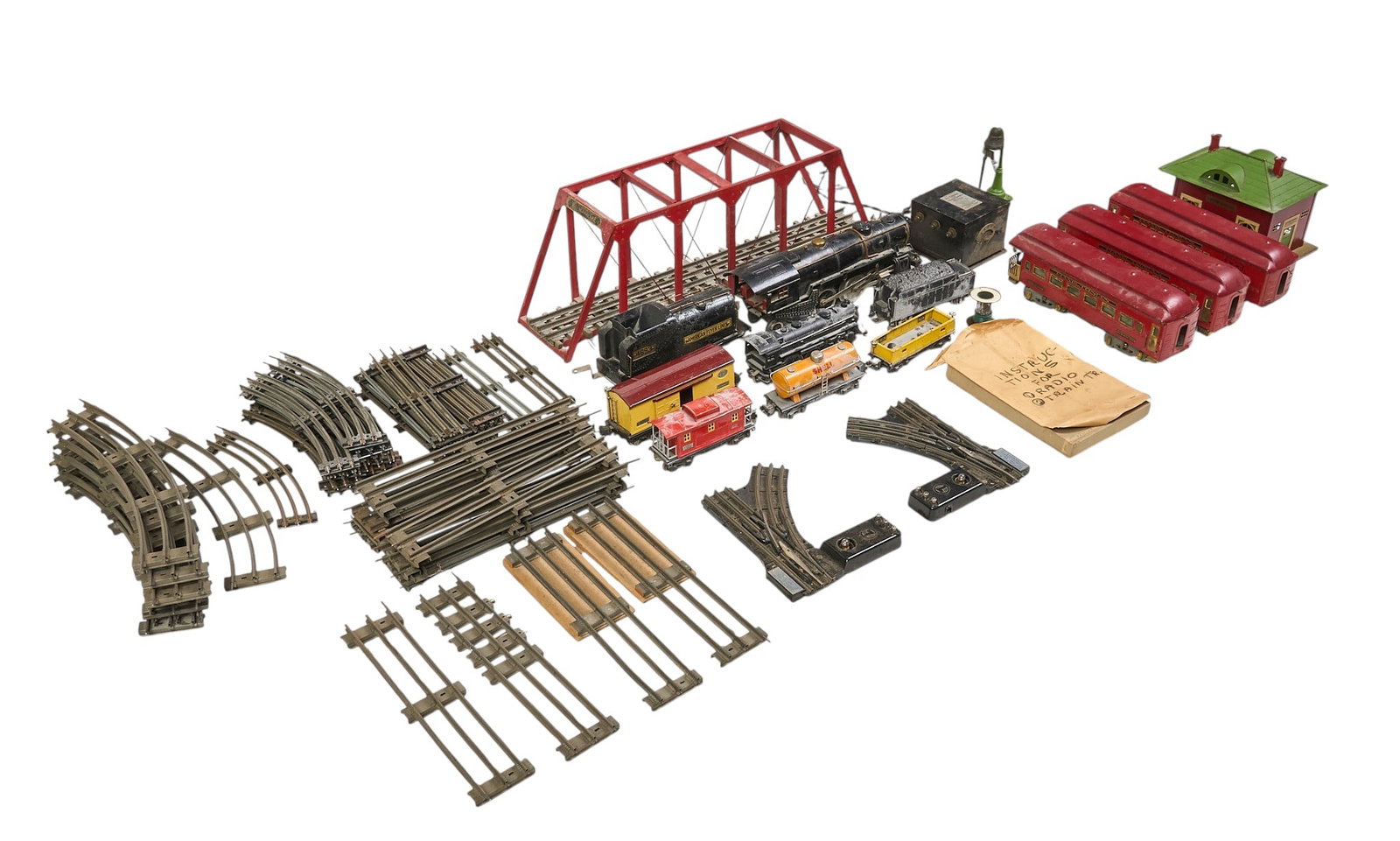 Collection of Vintage Toy Train Models: Collection of vintage toy trains models, includes locomotives, passenger cars, freight cars, a red truss bridge, train station, and numerous track pieces height 9 in. x width 28 in. x 
